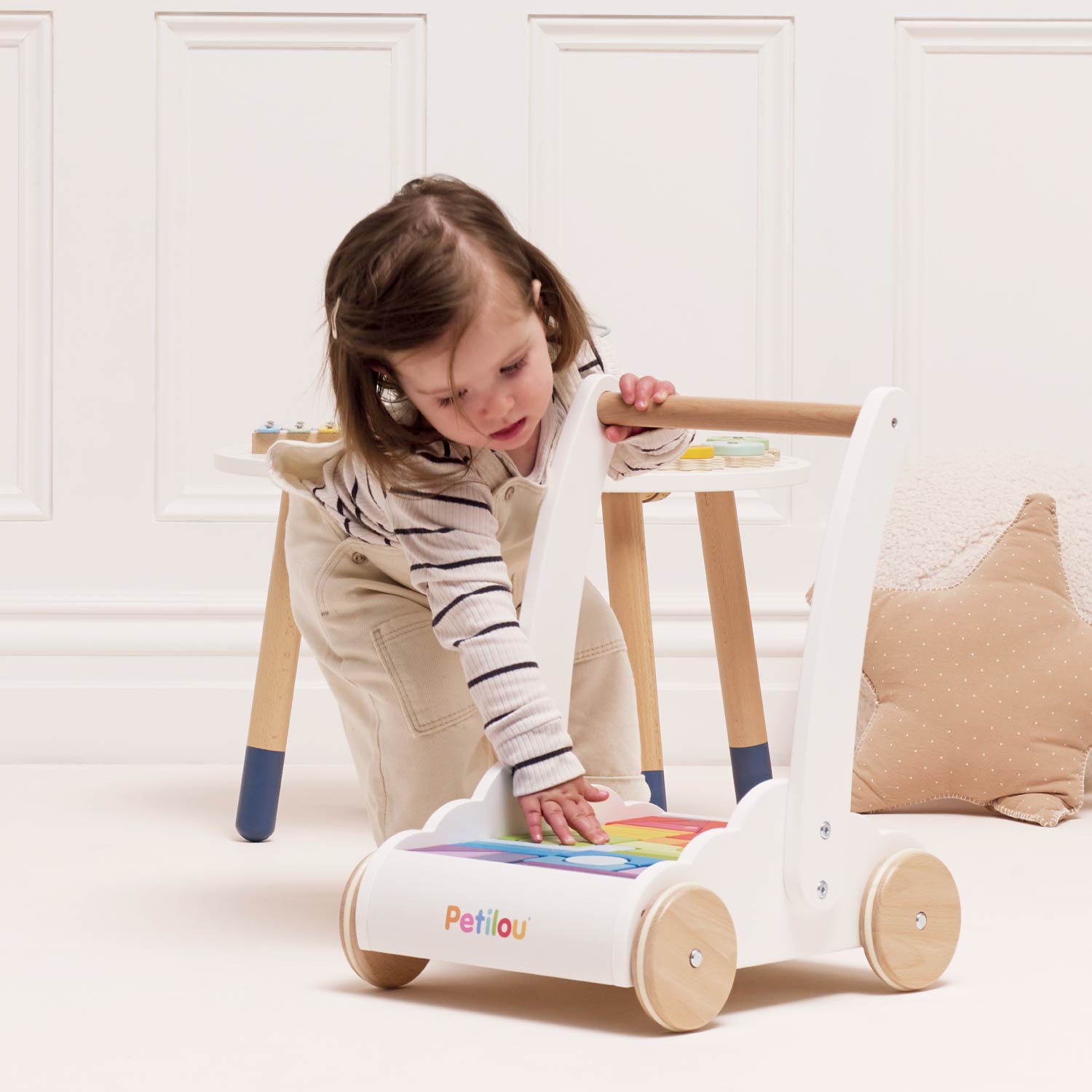 Child playing with a colorful toy walker indoors