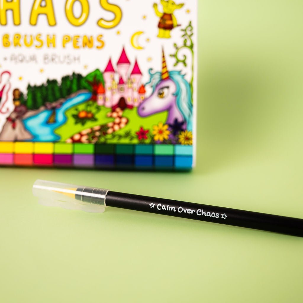 Brush pen with 'Calm Over Chaos' text in front of a colorful packaging on a green background