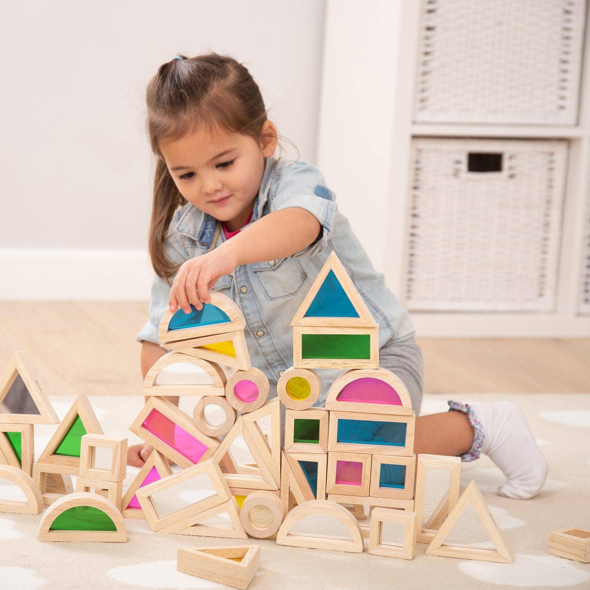 Child playing with colorful wooden building blocks on a light surface.