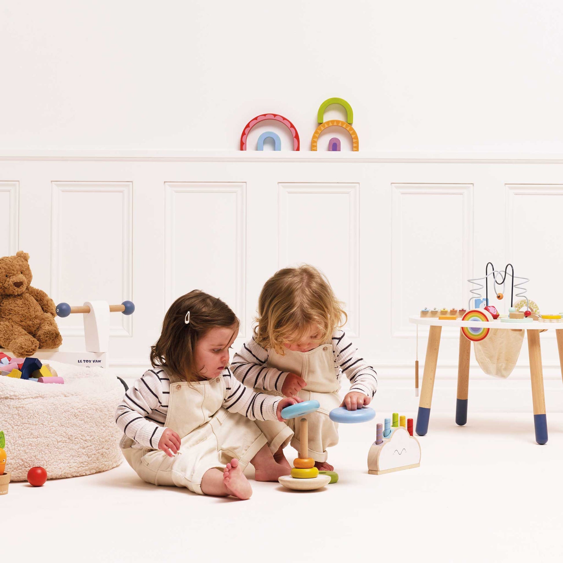 Two children playing with colorful toys in a bright room.
