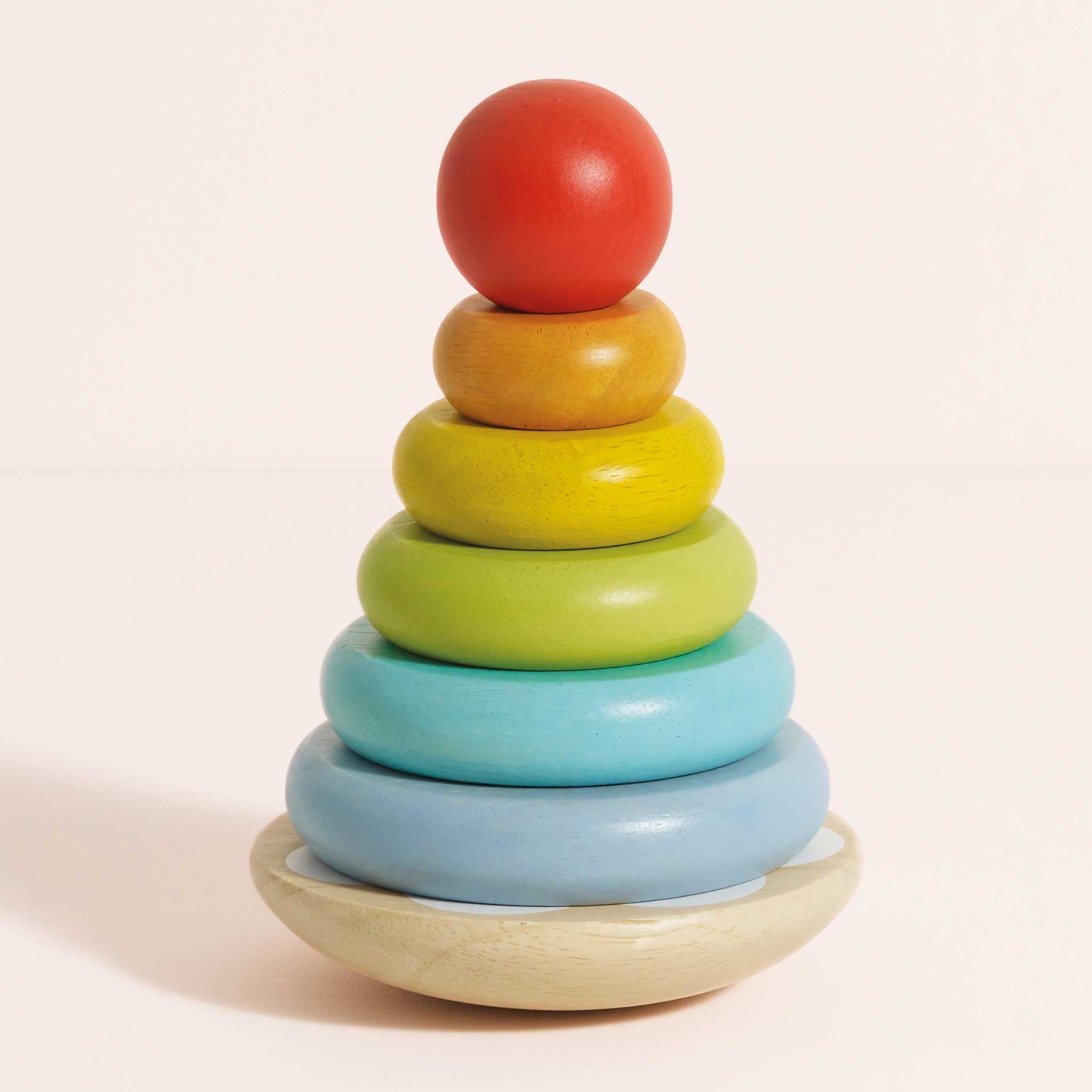 Colorful wooden stacking toy on a light pink background