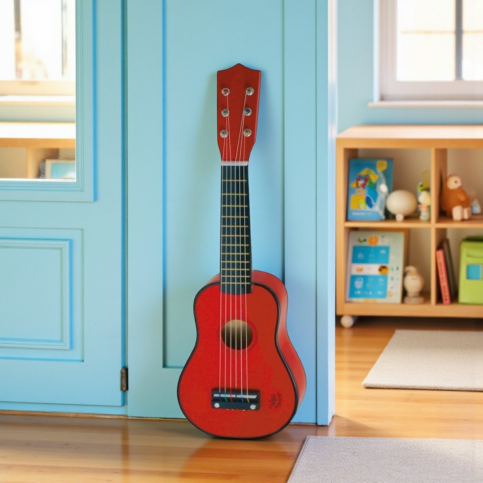 Red child guitar against a blue wall with a wooden shelf in the background