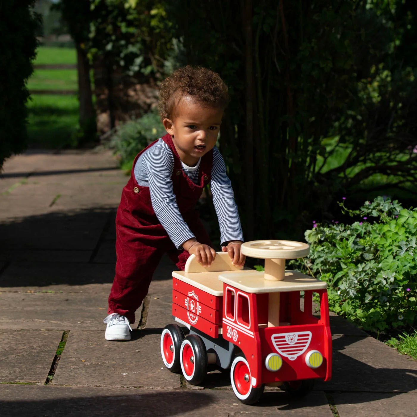 Child playing with a red toy truck outdoors