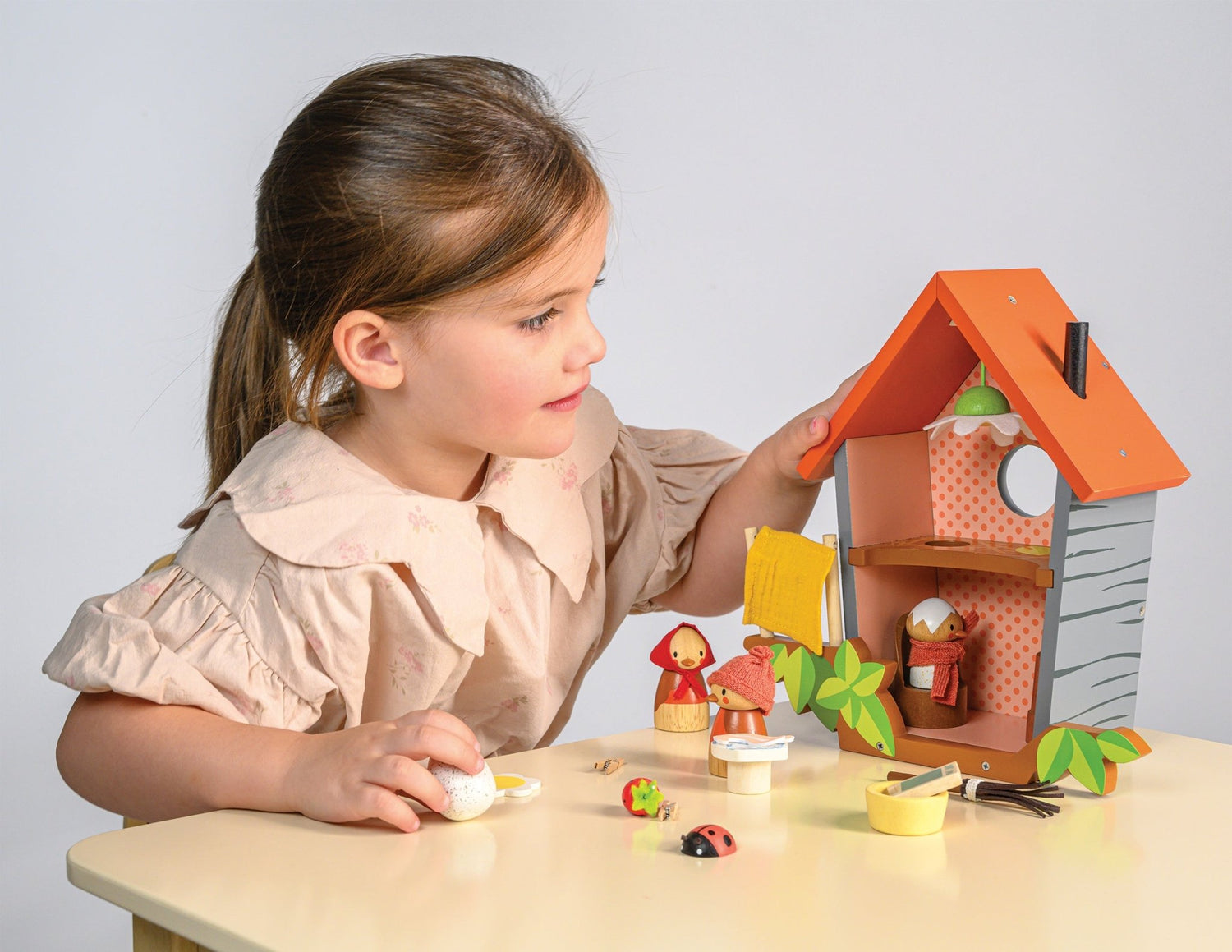 Child playing with a toy house and figures on a table