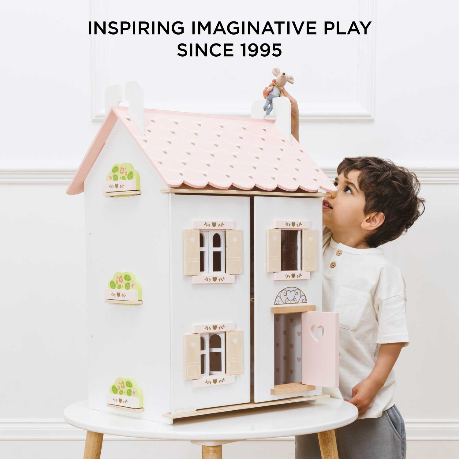 Child playing with a dollhouse, inspired by imaginative play since 1995