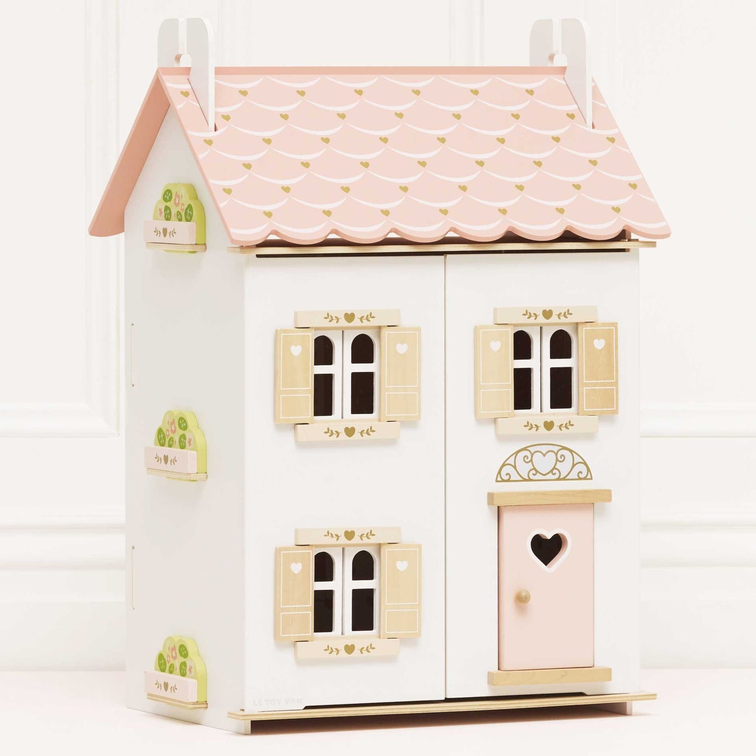 Small wooden dollhouse with a pink roof and white walls on a white background