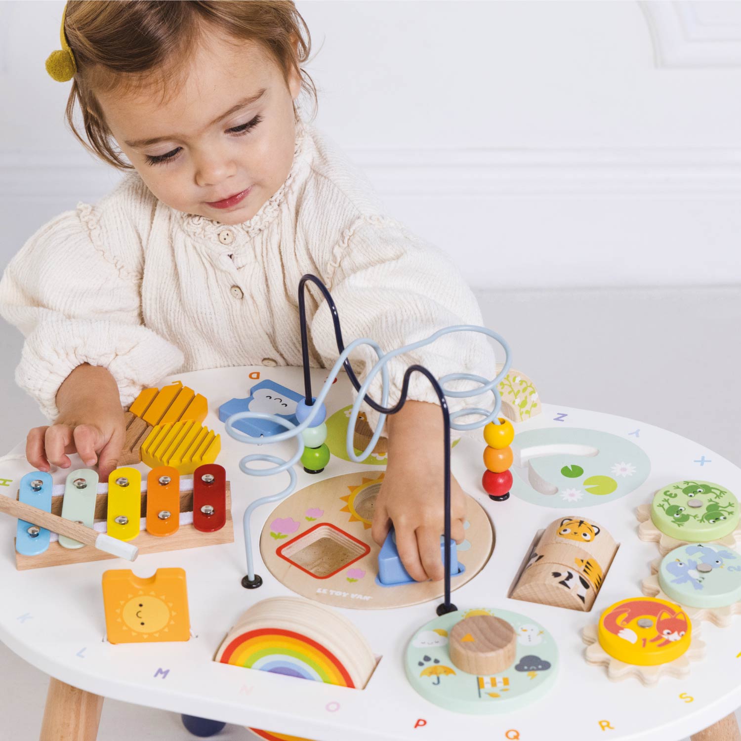Child playing with a variety of wooden toys on a table.