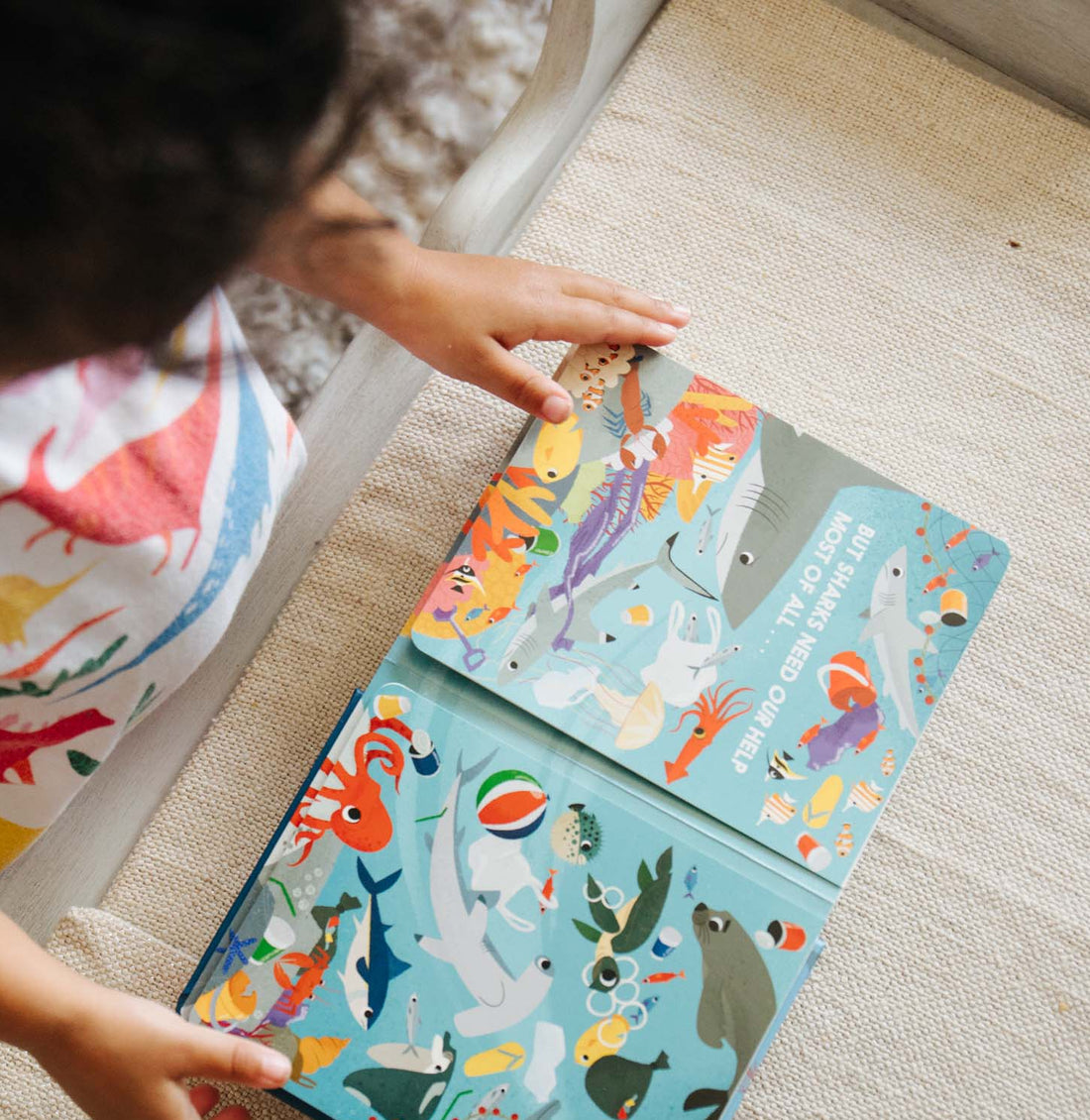 Child reading a colourful animal-themed book on a carpeted floor