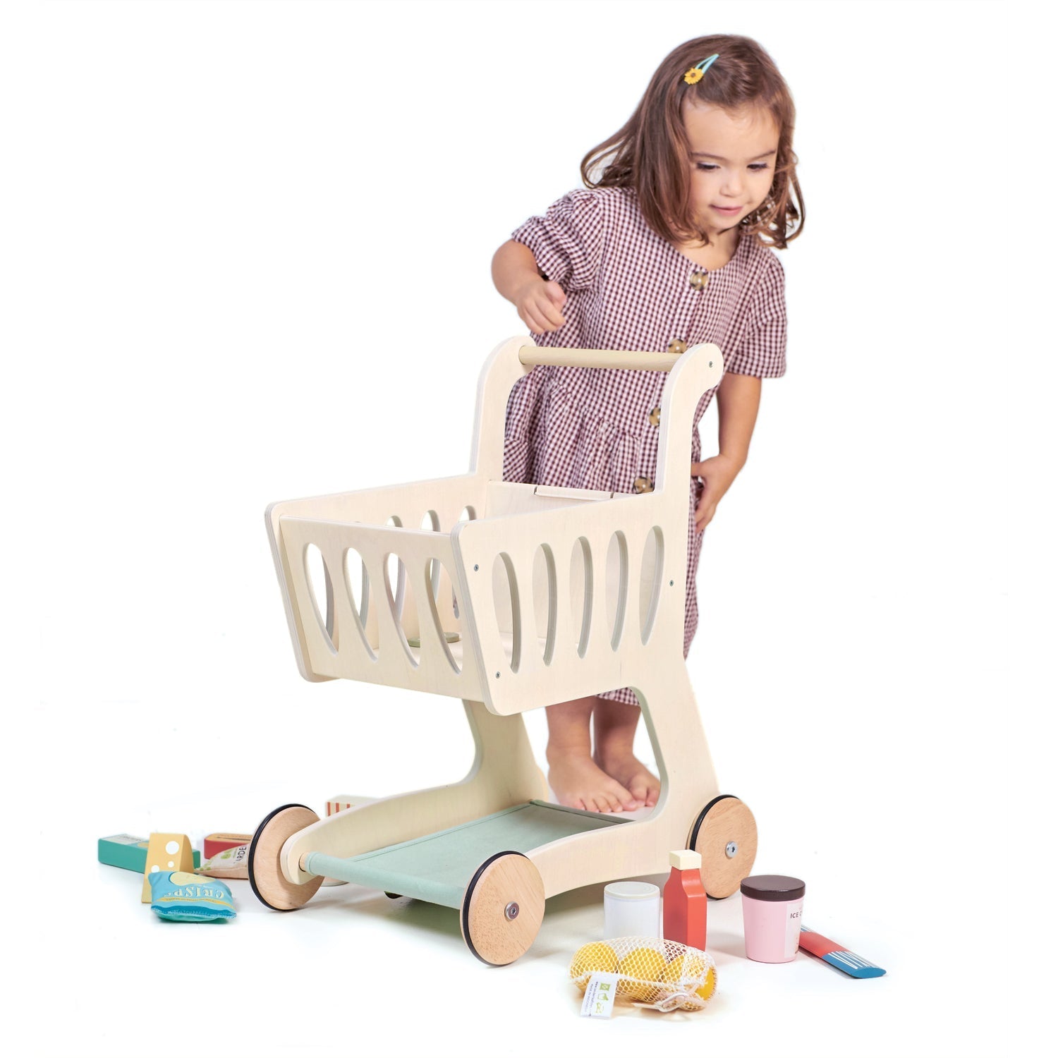 Child playing with a wooden toy shopping cart on a white background
