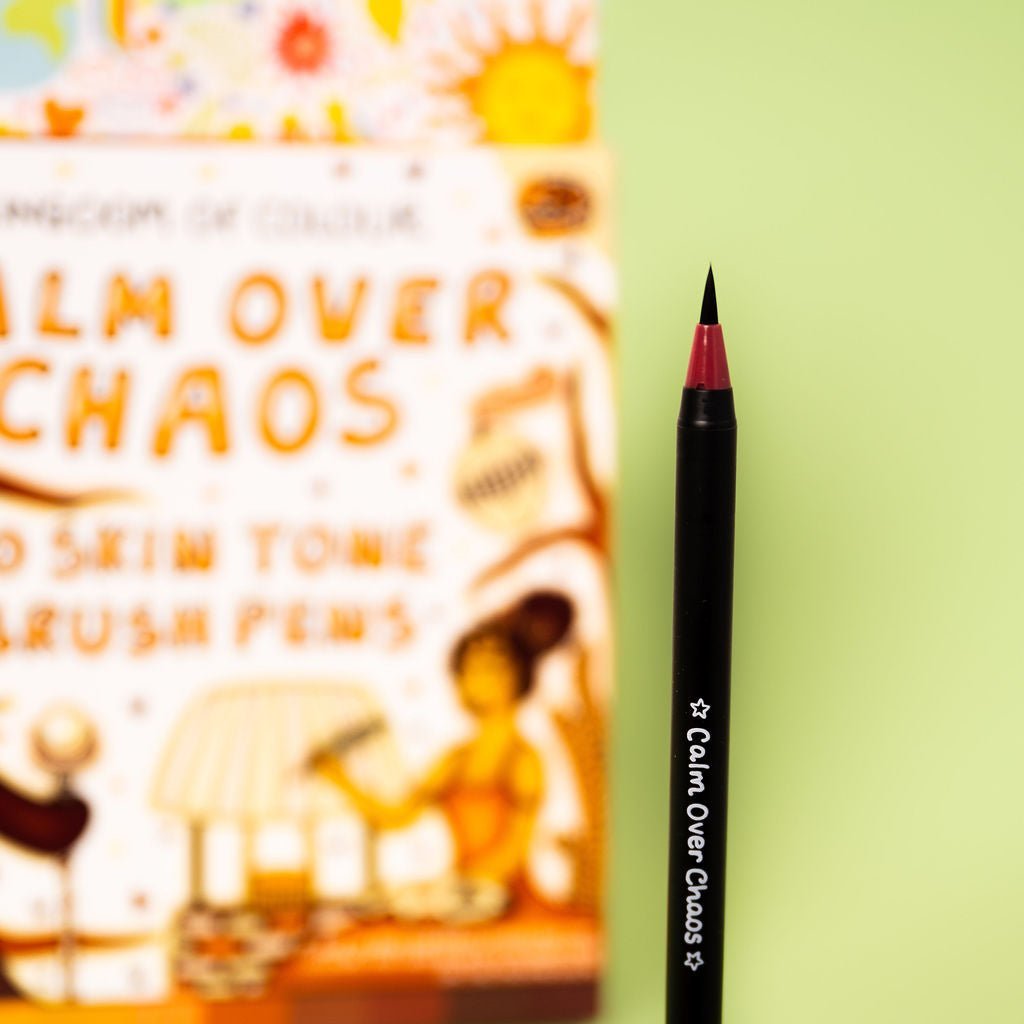 Black eyeliner pencil with 'Calm Over Chaos' branding next to a colorful book titled 'Calm Over Chaos'.