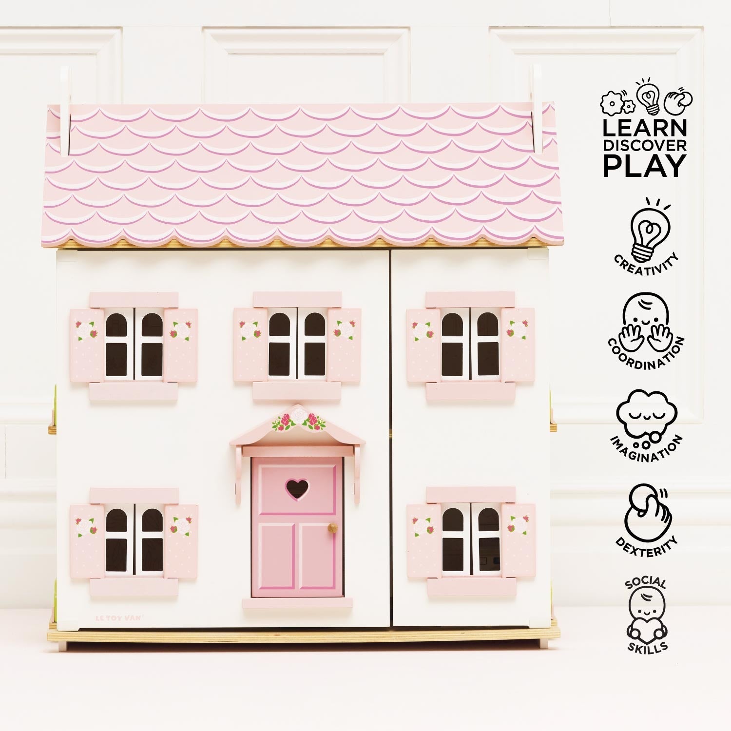 Pink toy house with a heart-shaped door on a white background, featuring 'Learn Discover Play' icons.