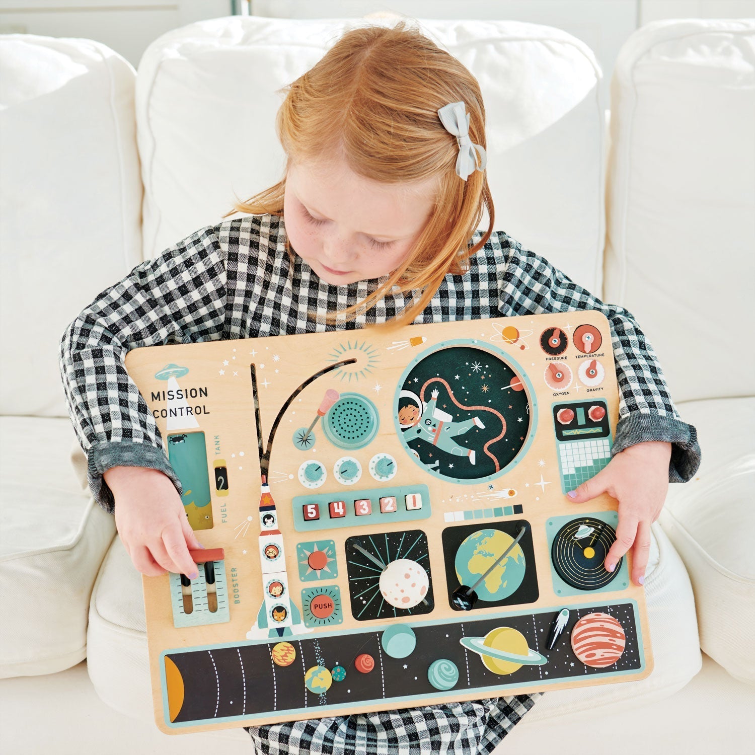 Child holding a space-themed puzzle on a white couch