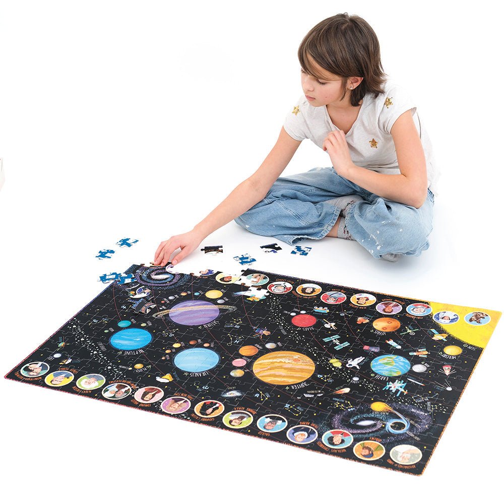 Child playing with a solar system-themed puzzle on a white floor
