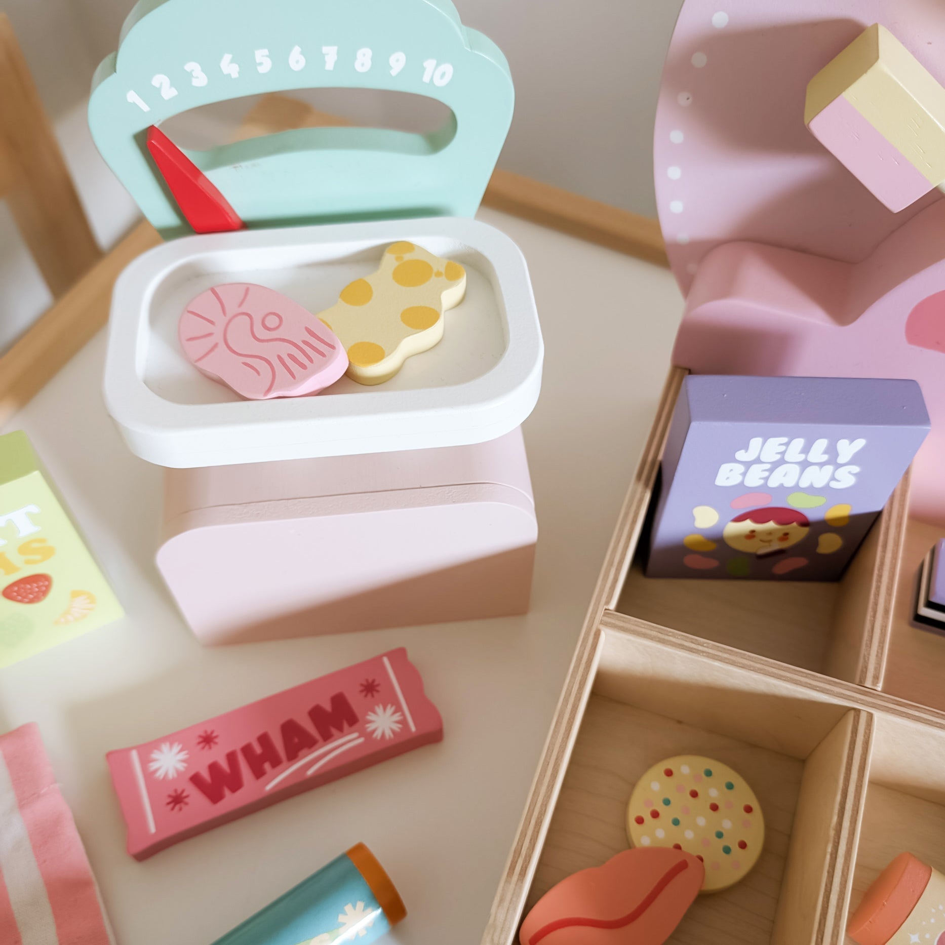 Toy candy store set with various toy candies and a box labeled 'Jelly Beans' on a wooden surface.