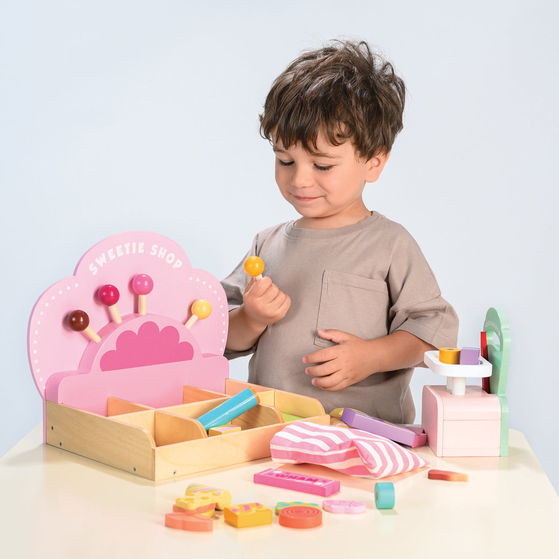 Child playing with a wooden toy set on a light blue background