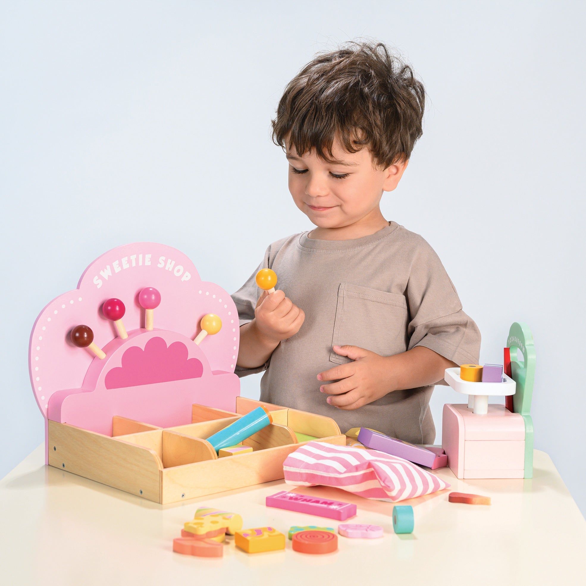 Child playing with a wooden toy set on a light blue background