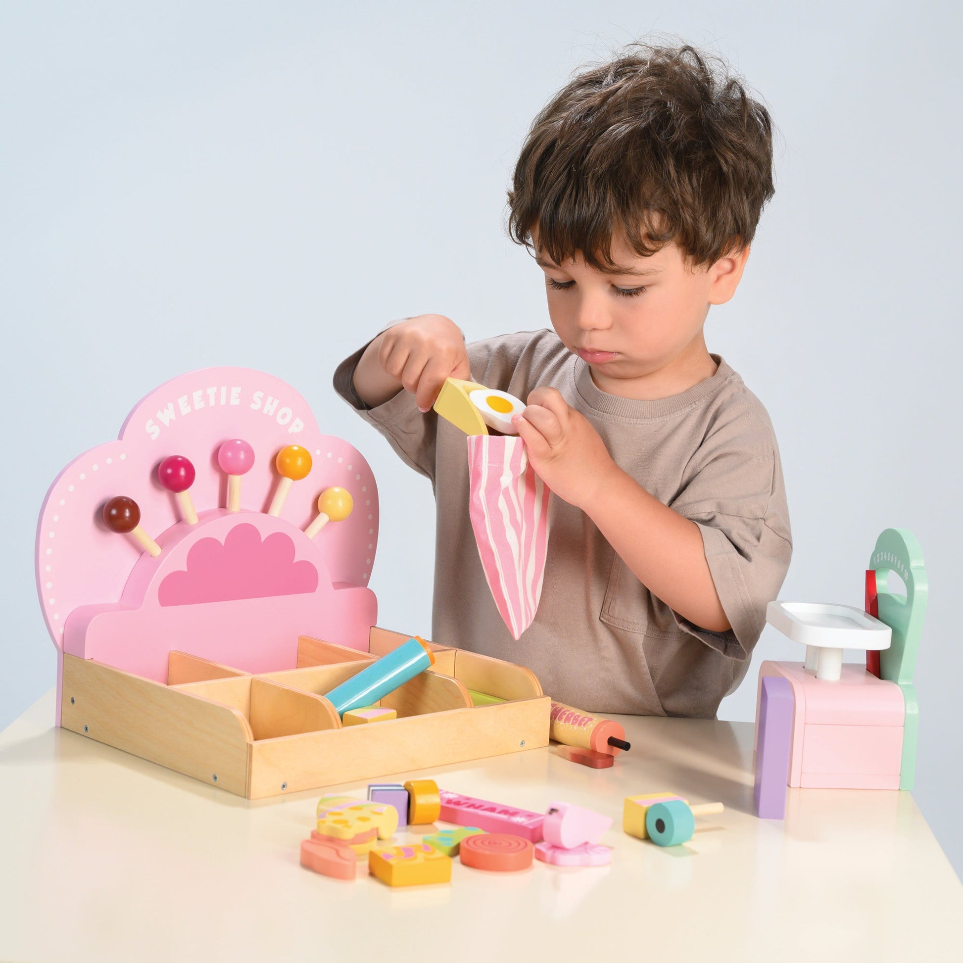 Child playing with a wooden toy set on a light surface with a plain background