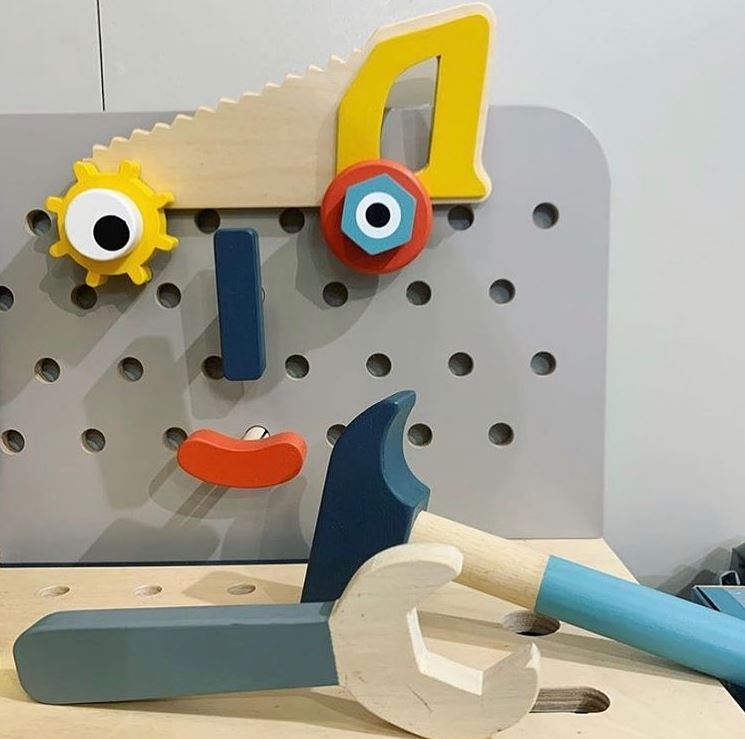 Colorful toy tool set on a wooden surface with a pegboard background