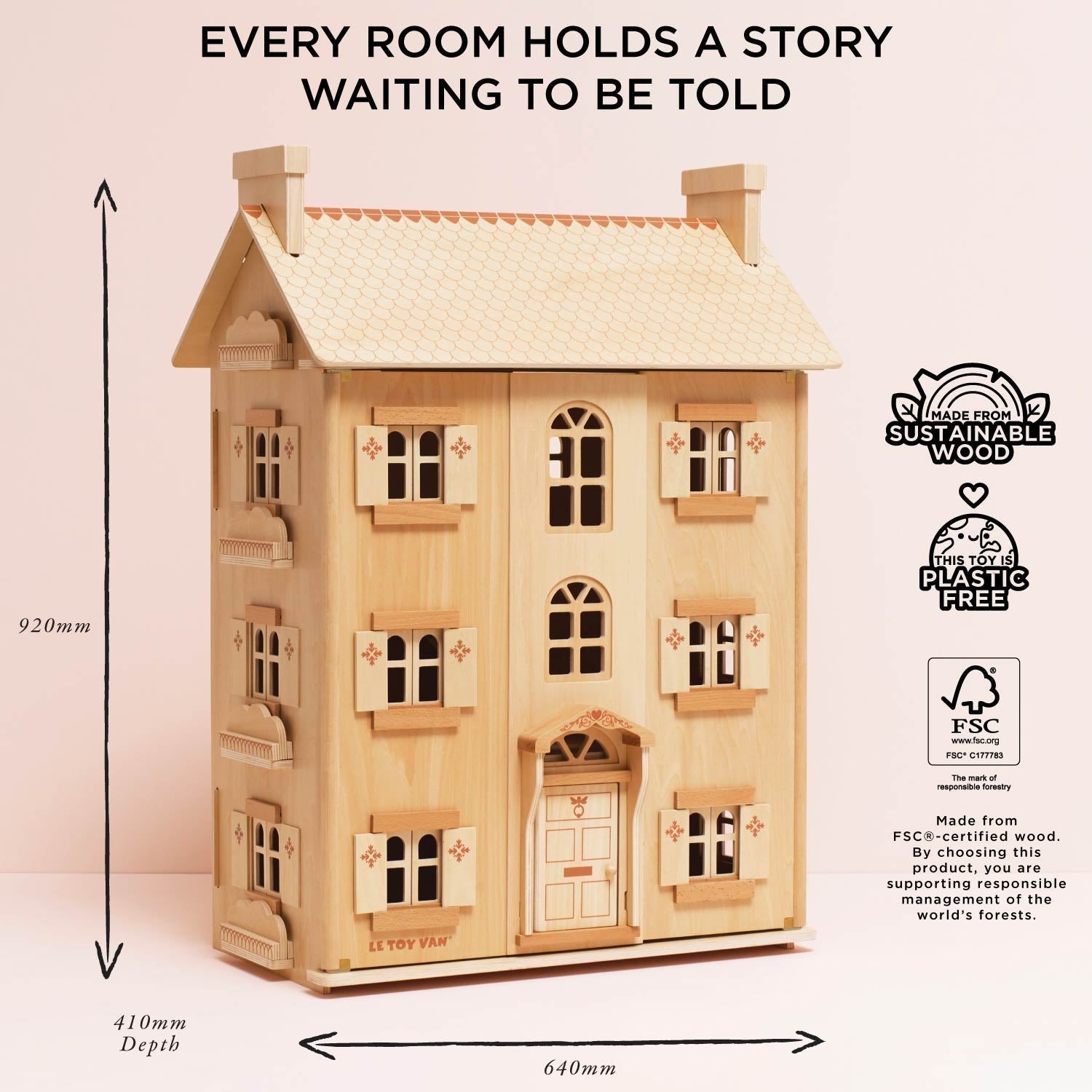 Wooden dollhouse with dimensions and sustainability certifications on a light pink background