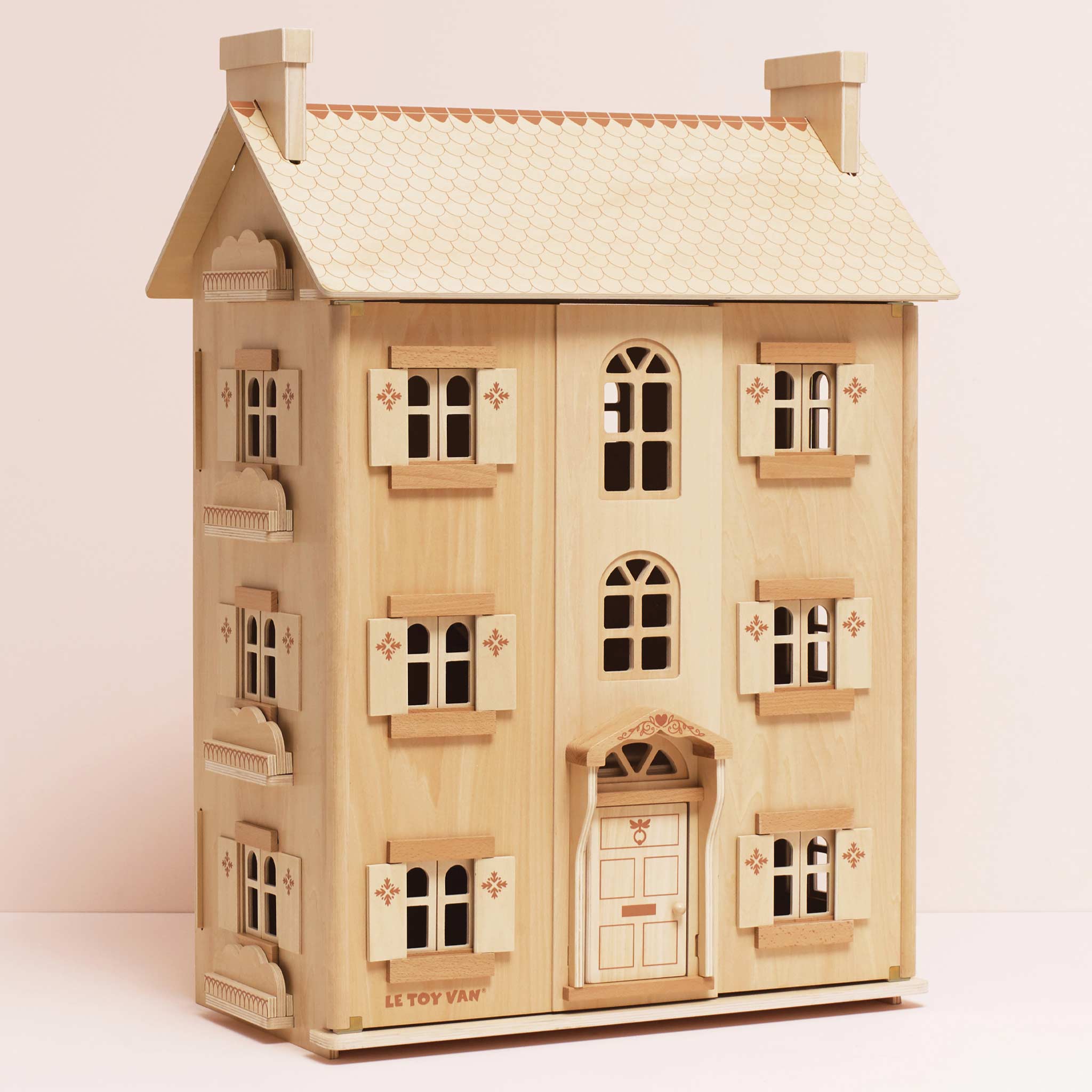 Wooden dollhouse with detailed windows on a light pink background