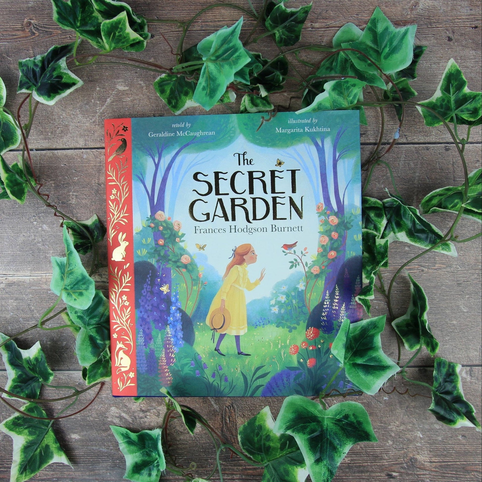 Book titled 'The Secret Garden' surrounded by green leaves on a wooden surface