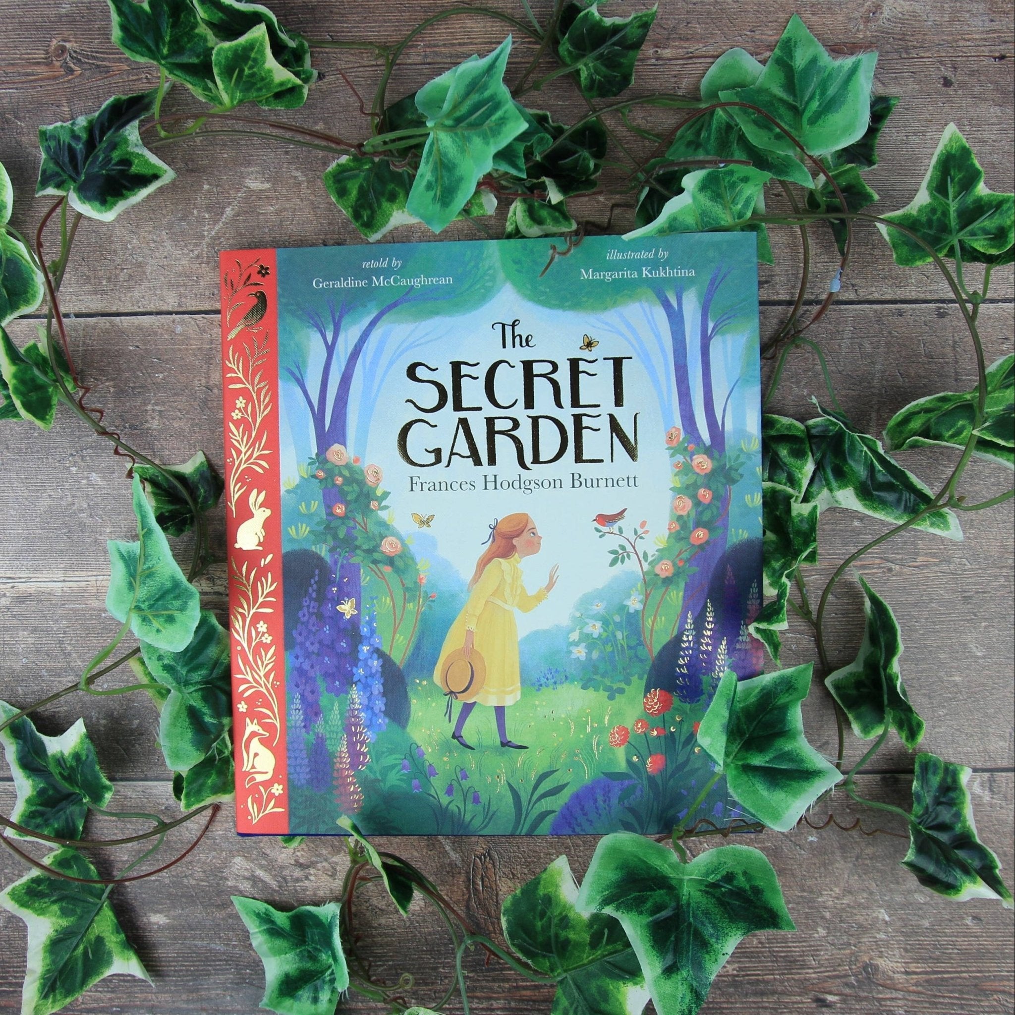 Book titled 'The Secret Garden' surrounded by green leaves on a wooden surface