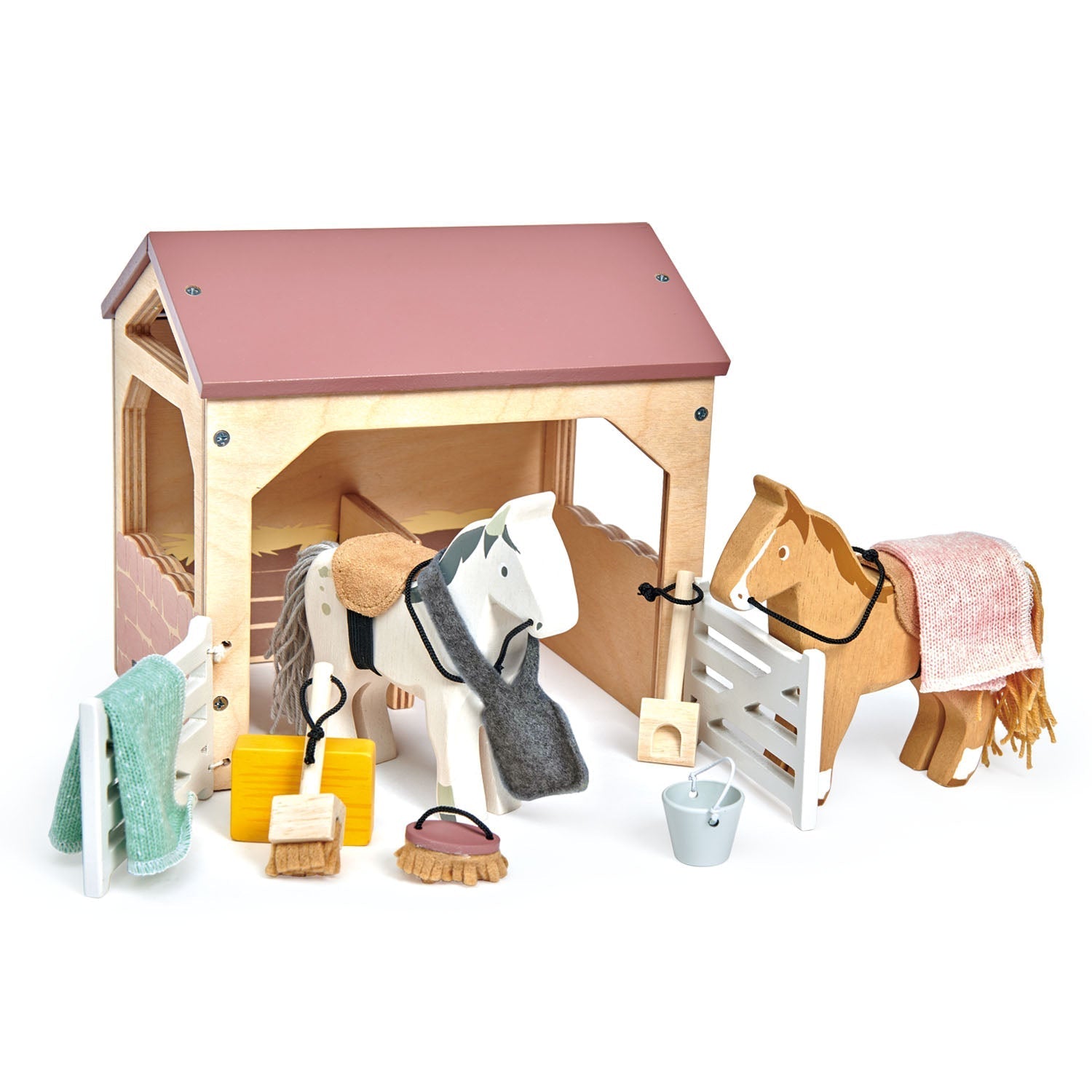 Toy stable with horses and grooming tools on a white background