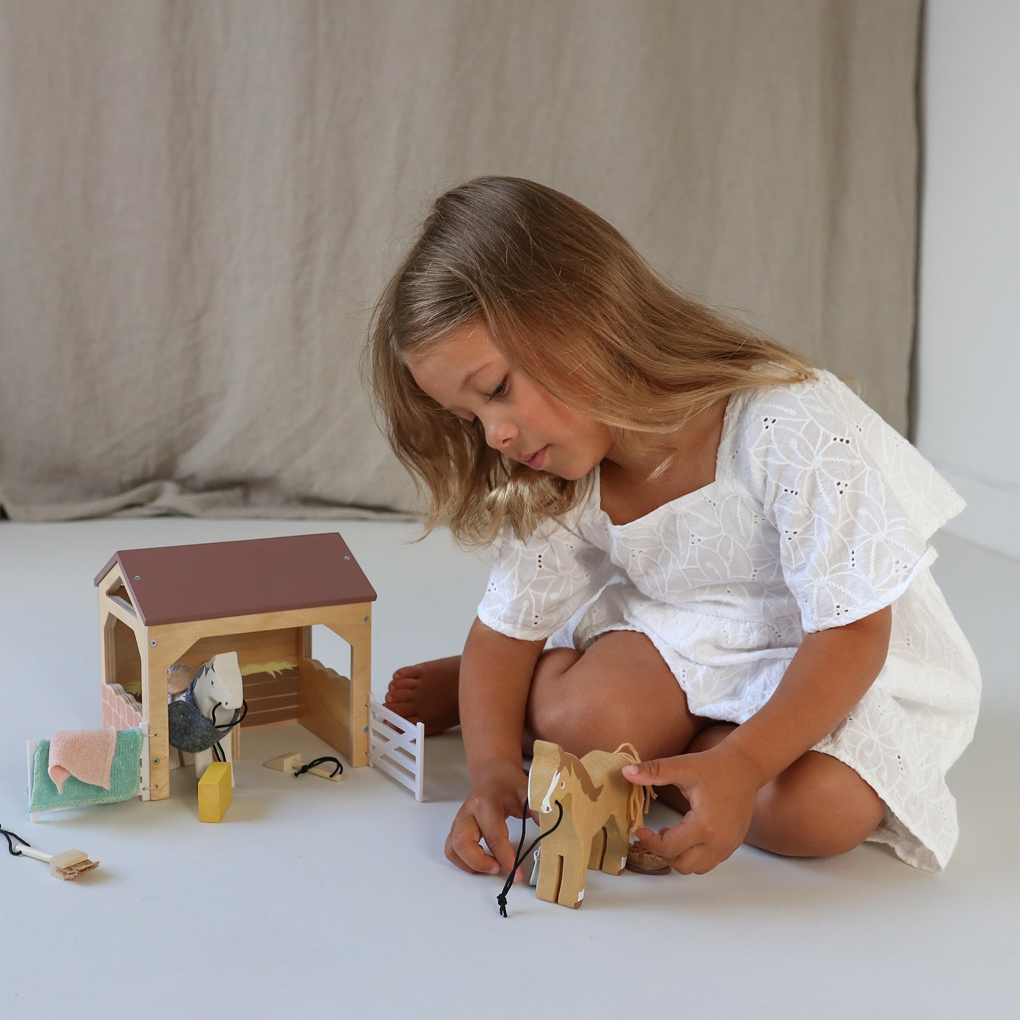 Young girl playing with wooden toys on a light surface.