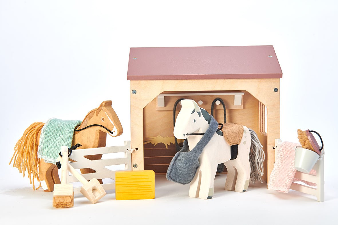 Toy horse stable set with two horses and a stable on a white background