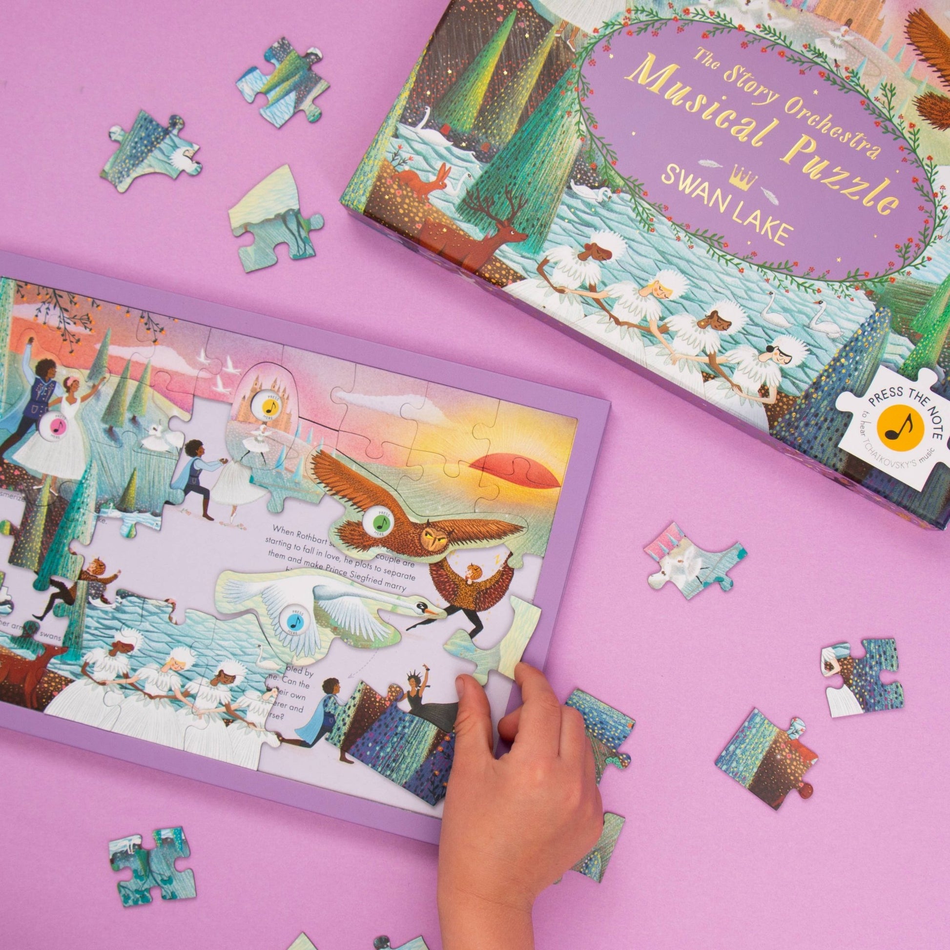Child playing with a Swan Lake puzzle on a pink surface