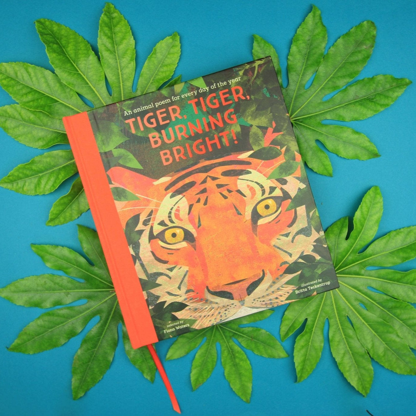 Book titled 'Tiger, Tiger, Burning Bright!' on green leaves against a blue background