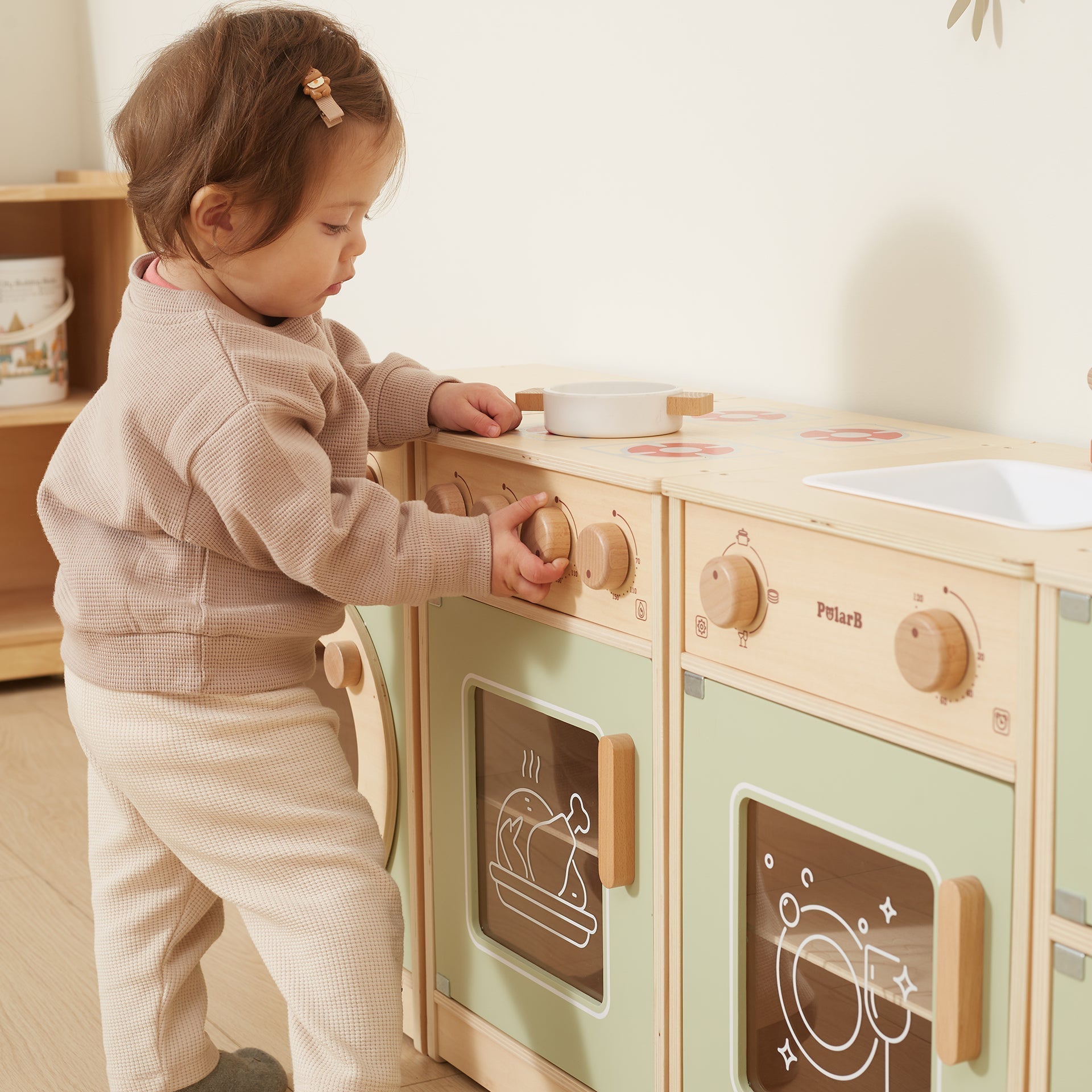 Child playing with a wooden toy kitchen set