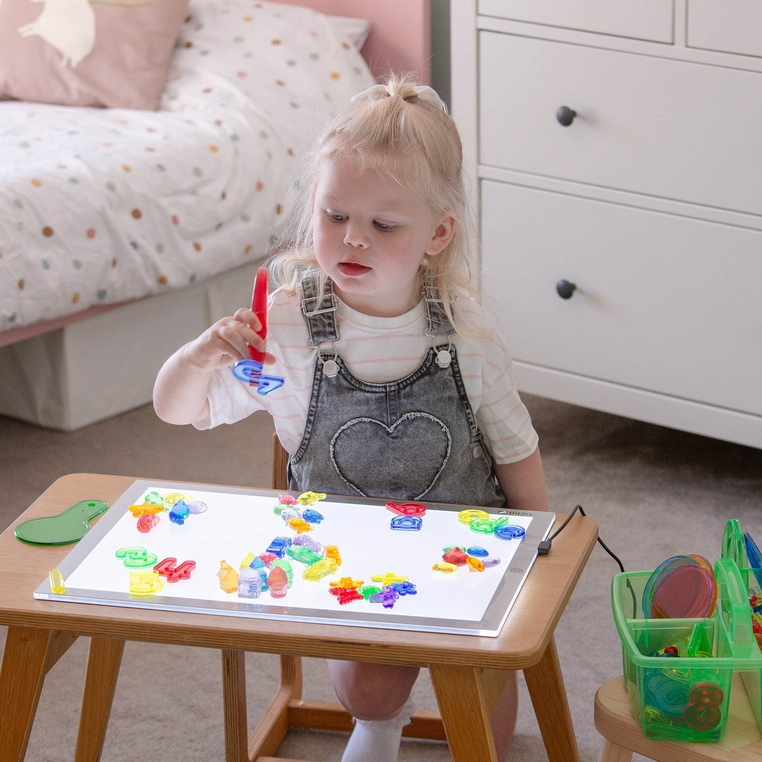 Child playing with colorful magnetic letters on a white board at a table.