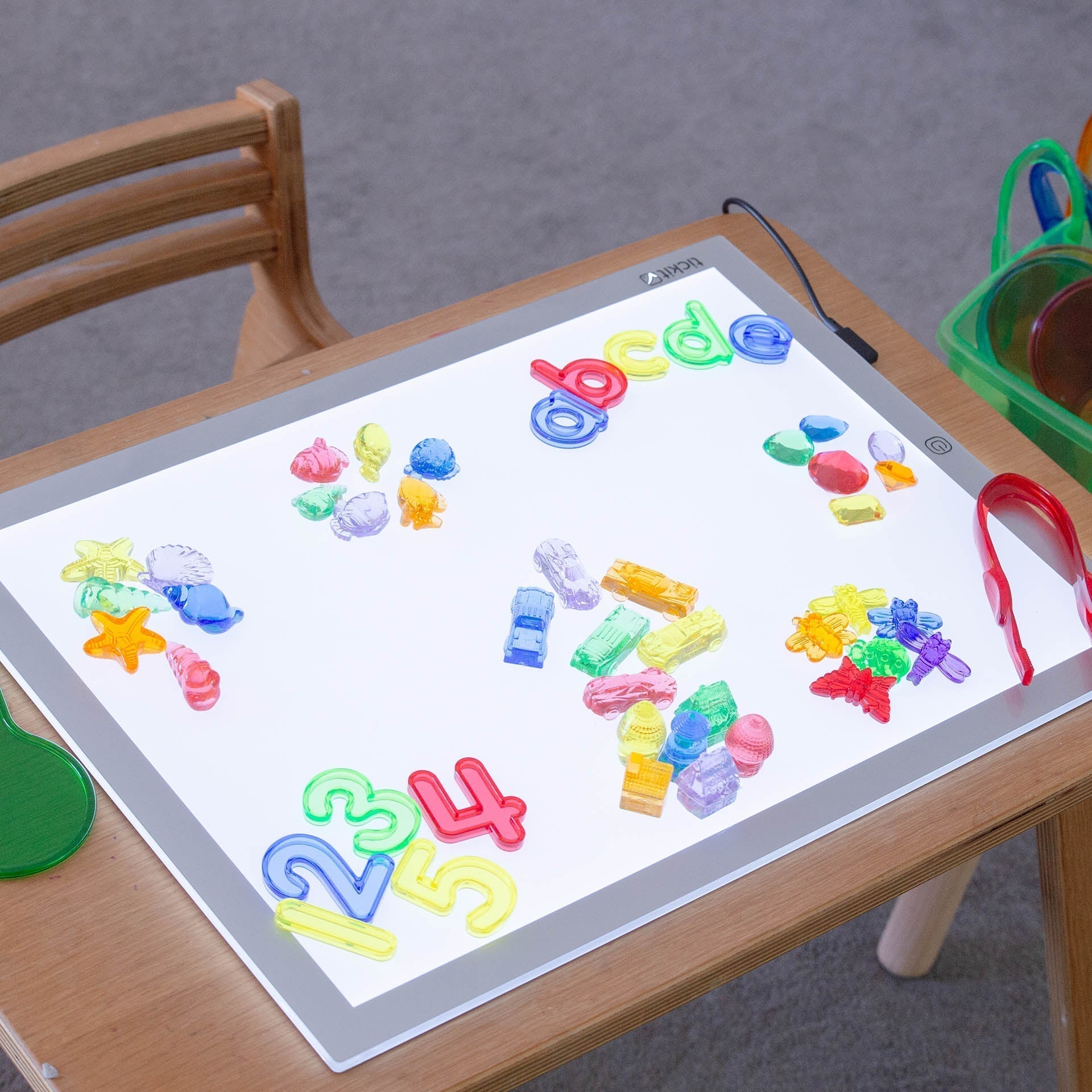 Light-up board with colorful letters and numbers on a wooden table.