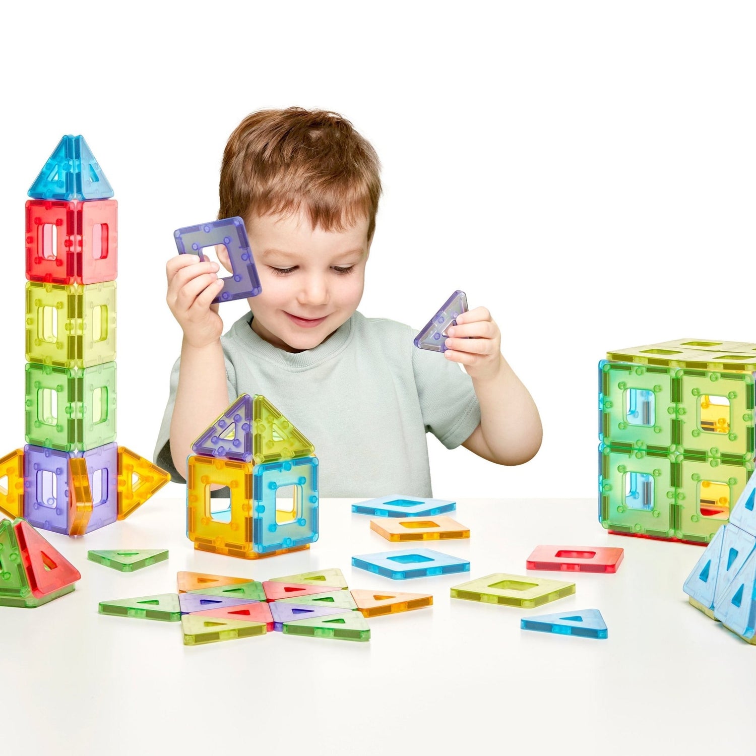 Child playing with colorful magnetic building blocks on a white background