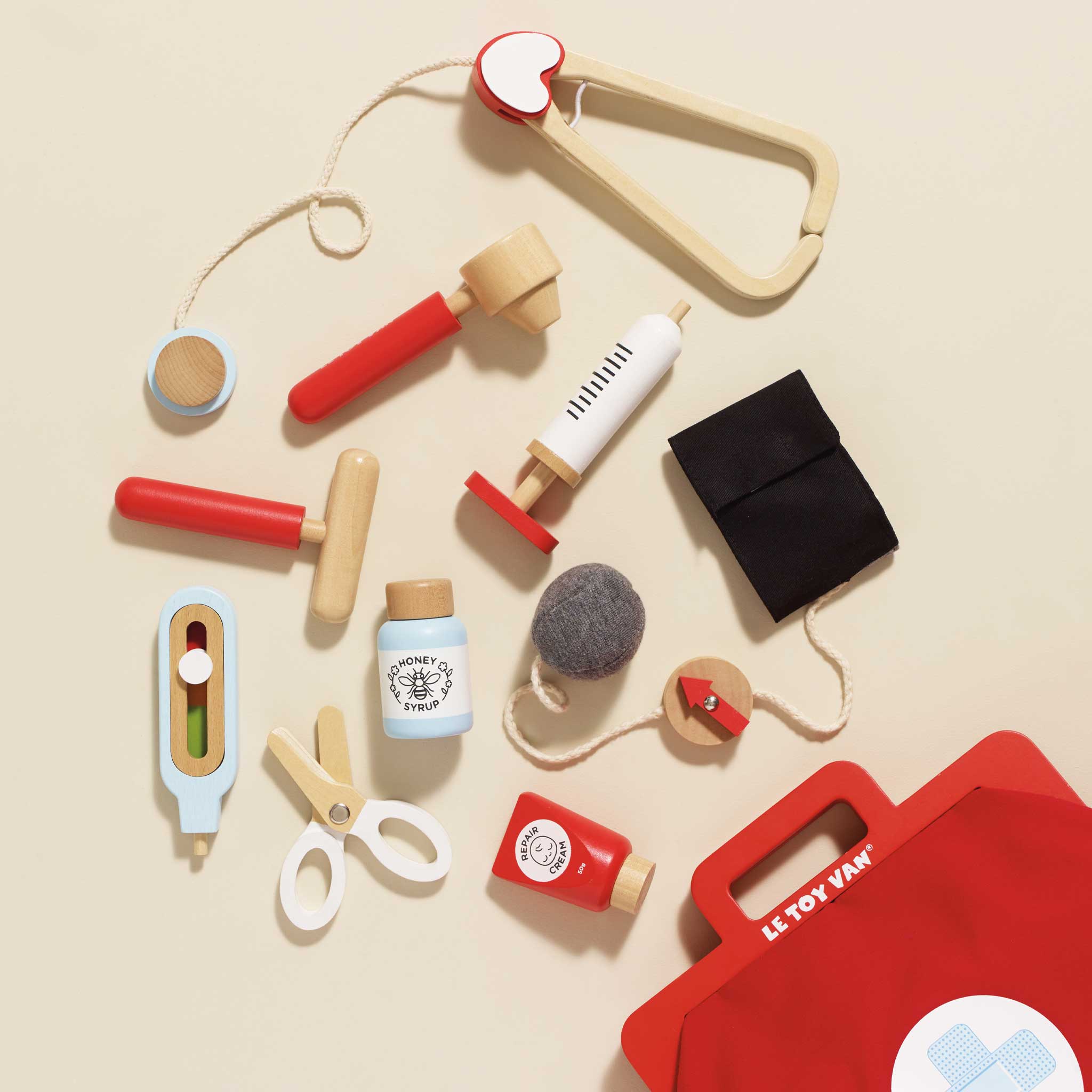 Collection of colorful toy kitchen utensils and tools on a beige background