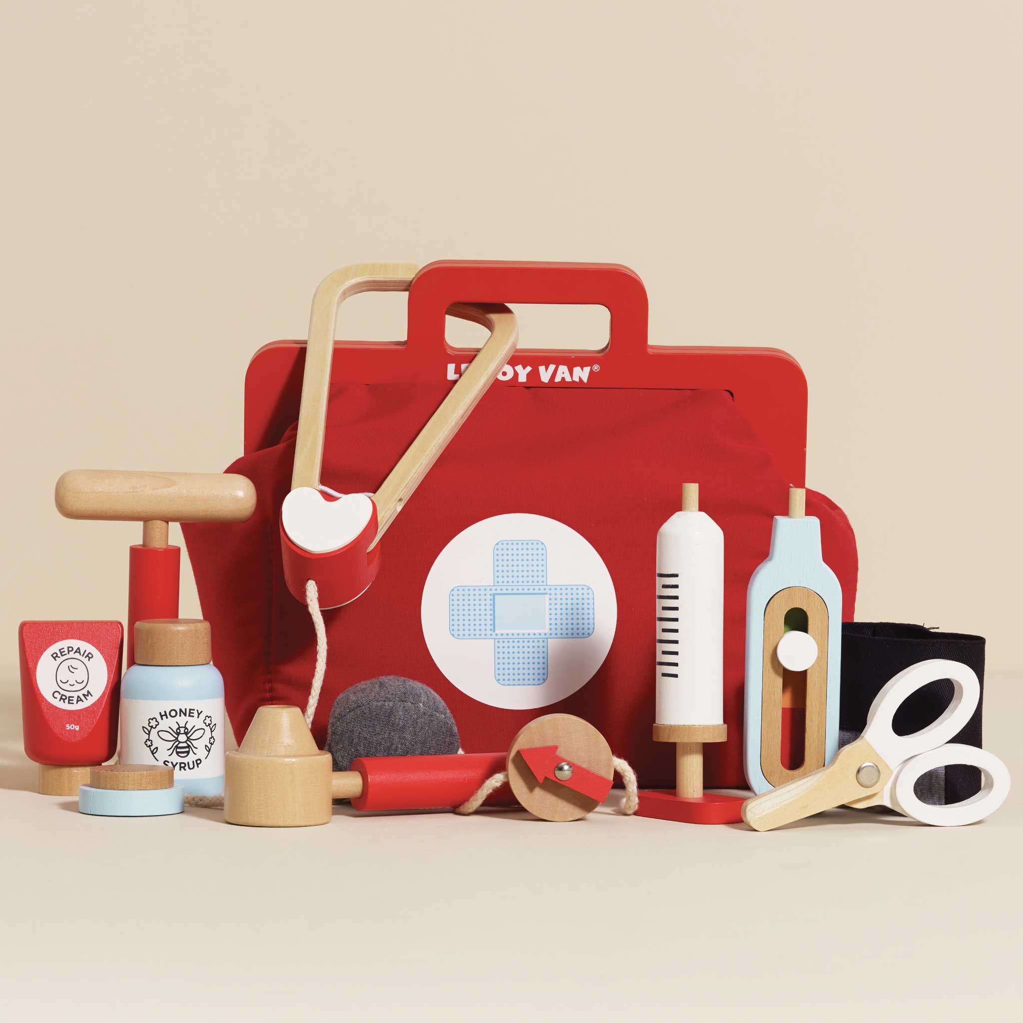 Red toy tool kit with various tools on a beige background