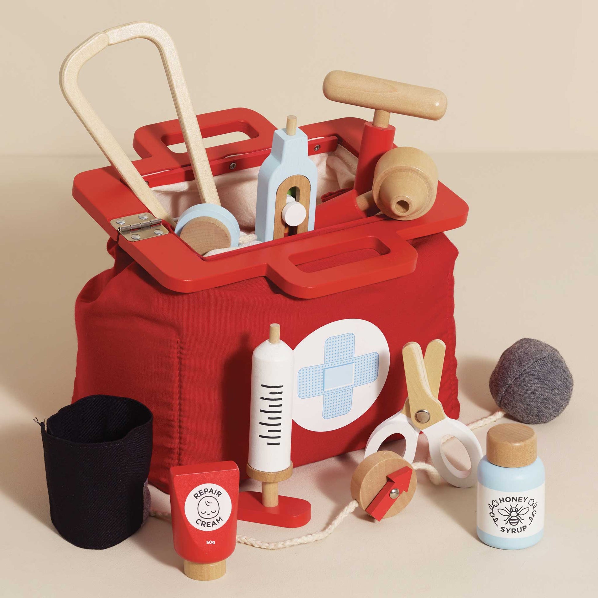 Red toy tool box with various wooden tools on a beige background