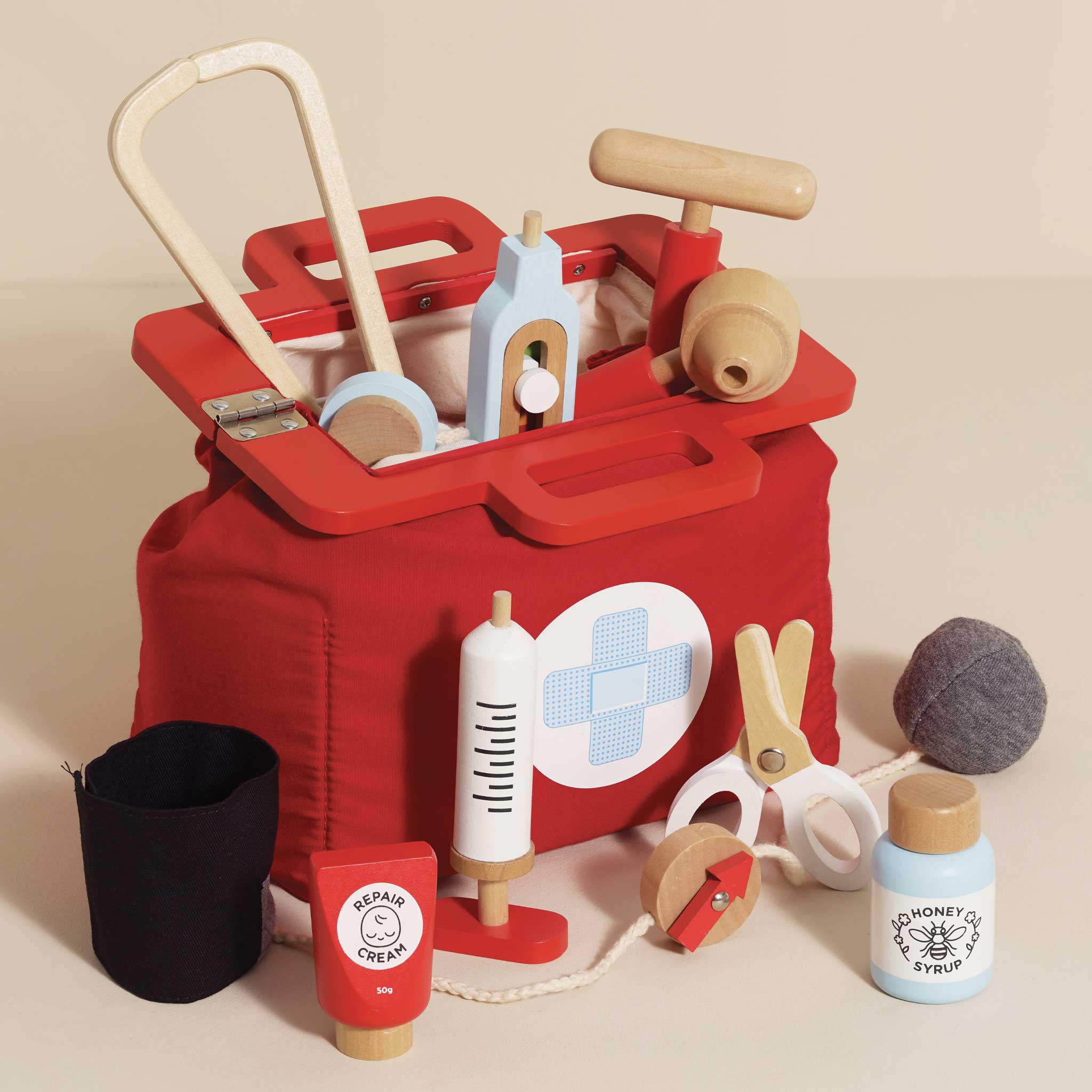 Red toy tool box with various wooden tools on a beige background