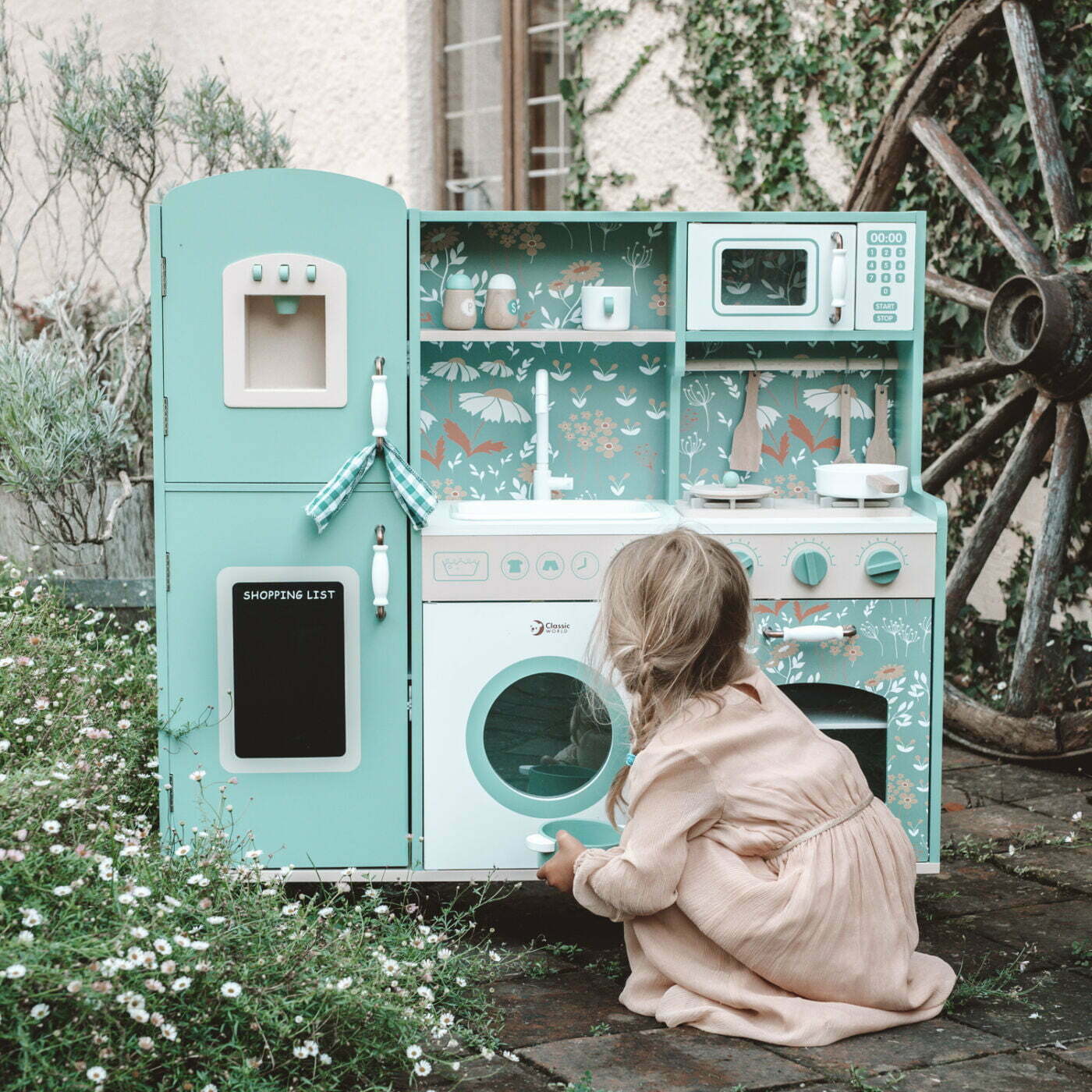 Child playing with a toy kitchen set outdoors