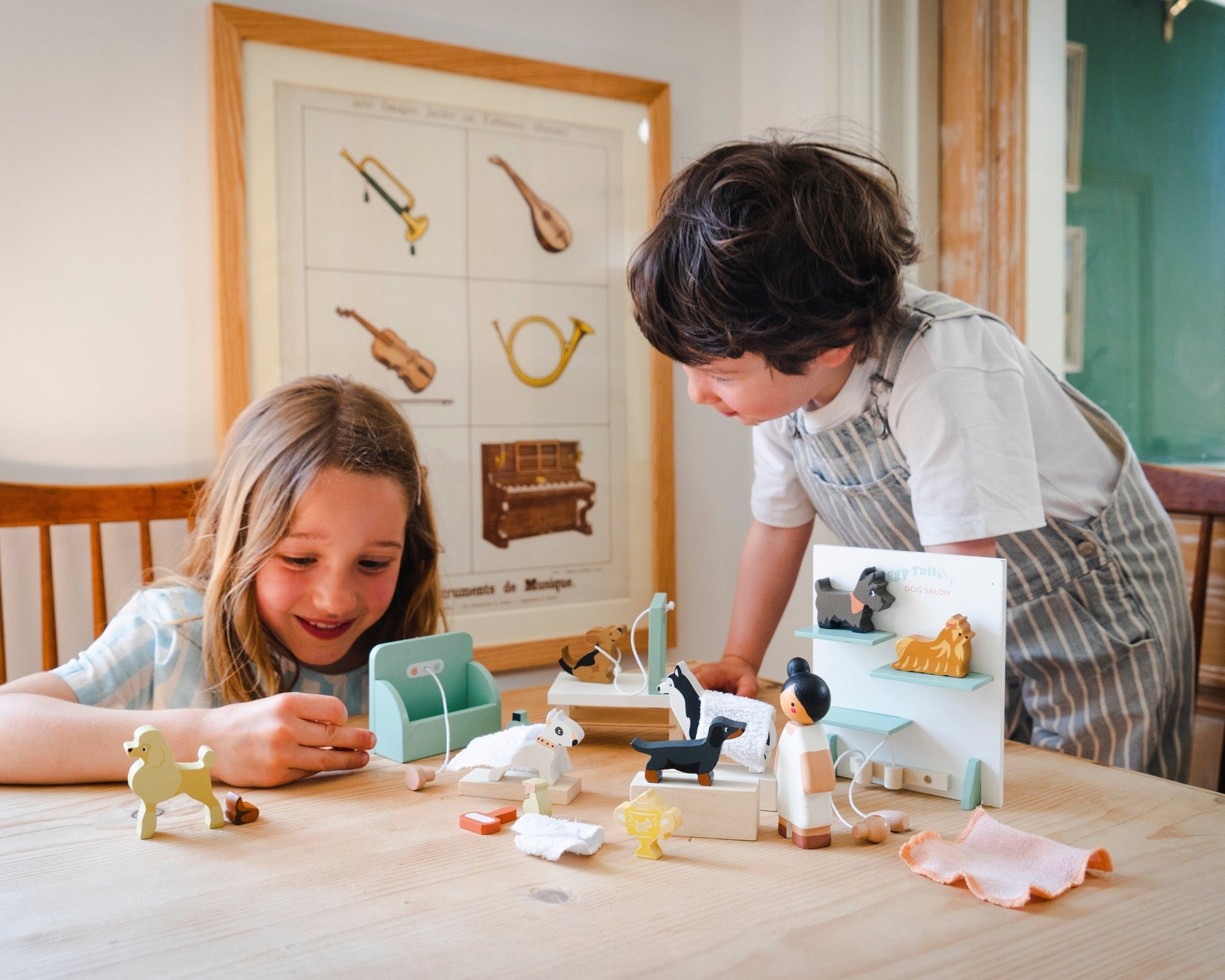 Two children playing with toys at a table in a room with a decorative wall poster.