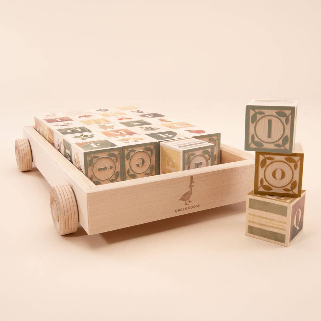 Wooden toy blocks with numbers and letters in a wooden cart on a beige background