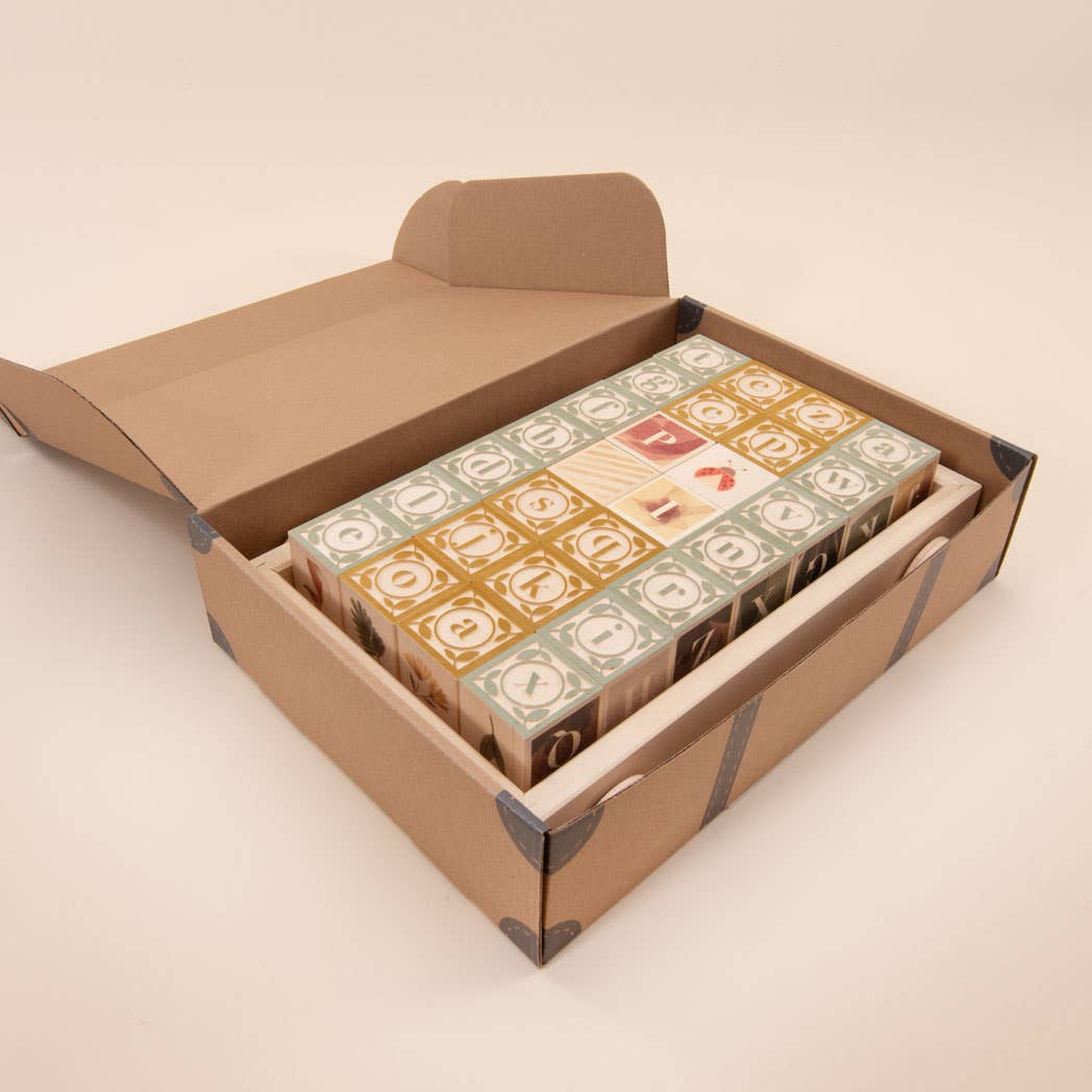 Open cardboard box containing multiple small boxes with decorative labels on a beige background