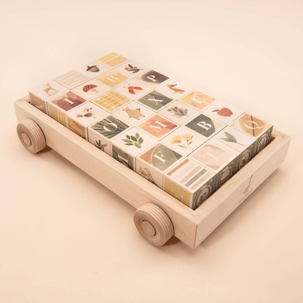 Wooden toy cart with alphabet blocks on a beige background