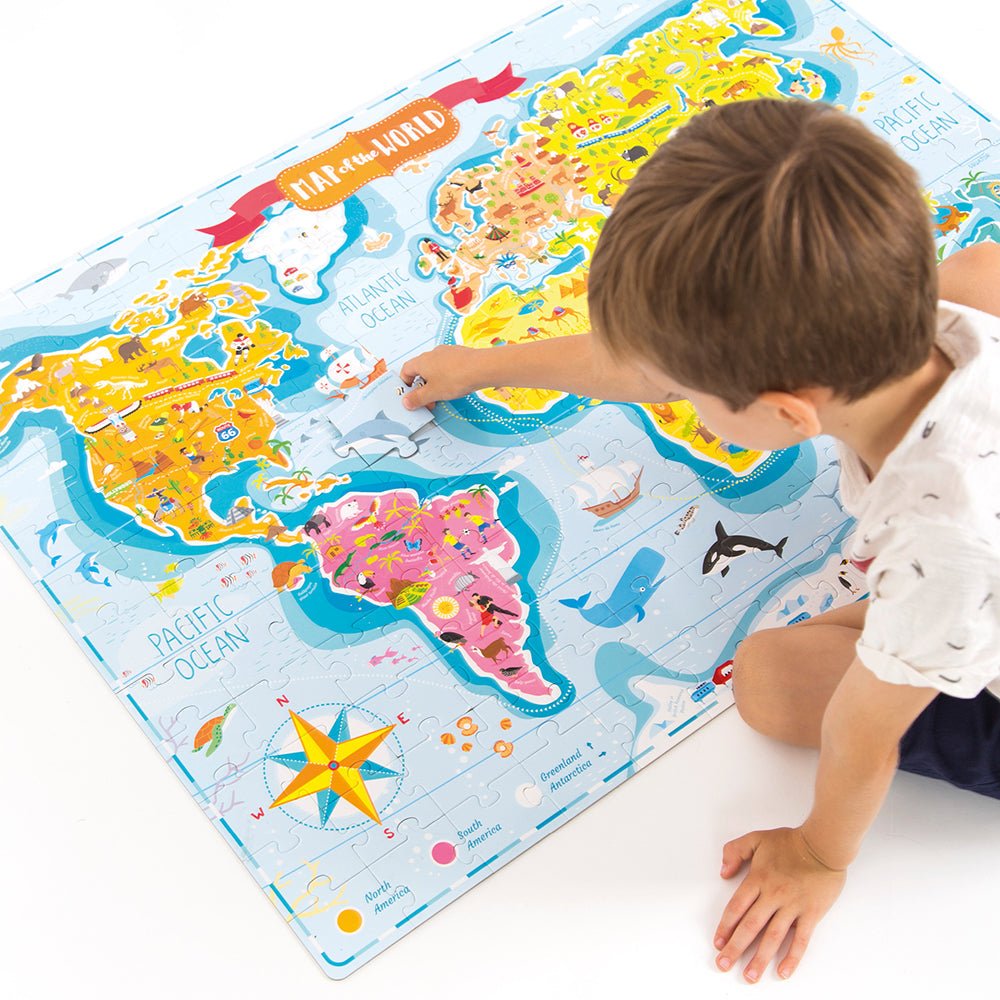Child playing with a colorful world map puzzle on a white surface