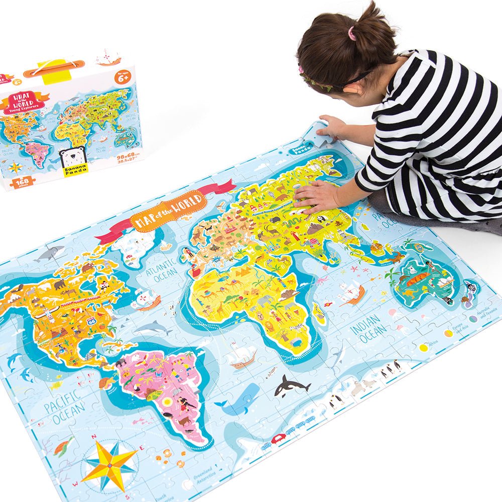 Child playing with a large world map puzzle on a white surface