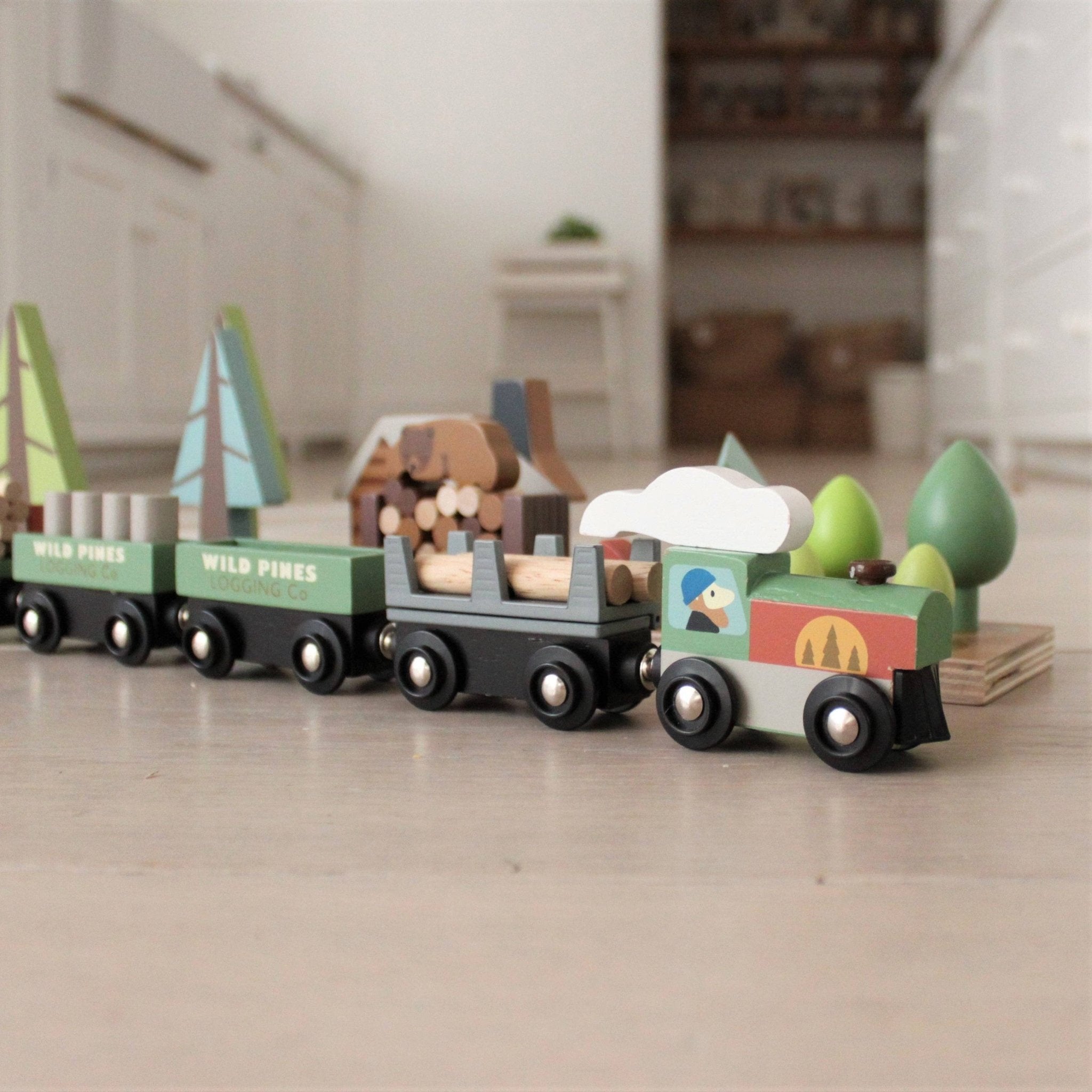 Wooden toy train set on a light wooden floor with a blurred indoor background