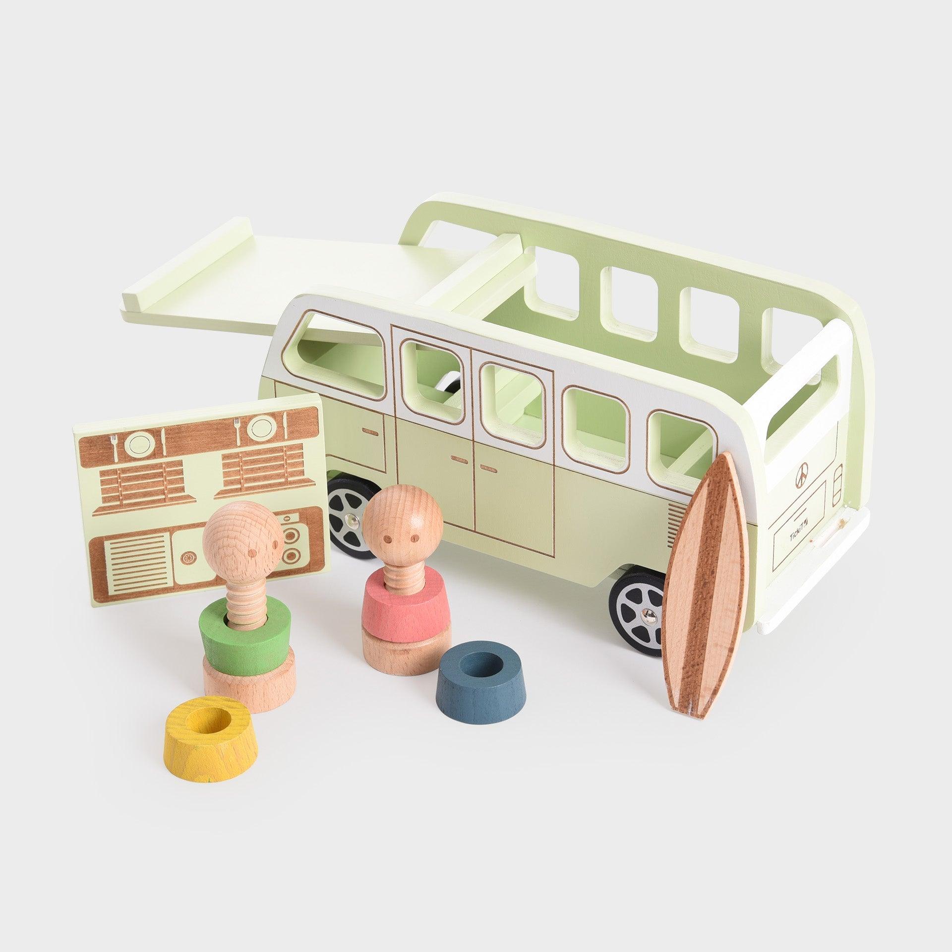 Wooden toy camper van with two dolls and a surfboard on a white background