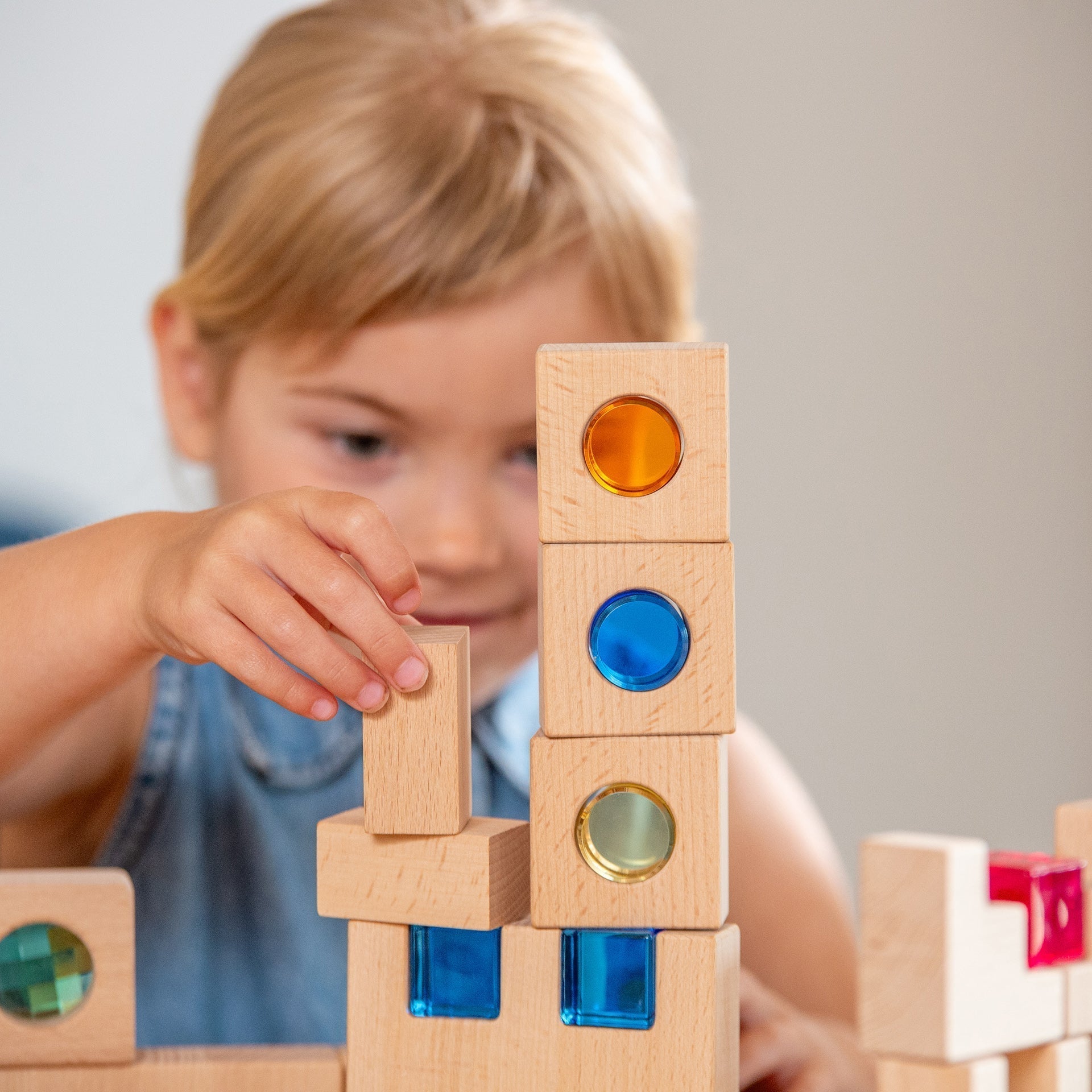 Child playing with wooden building blocks with colored circles.