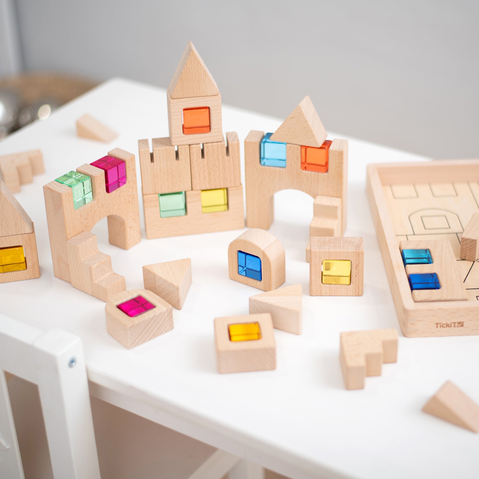 Wooden building blocks with colorful square inserts on a white surface